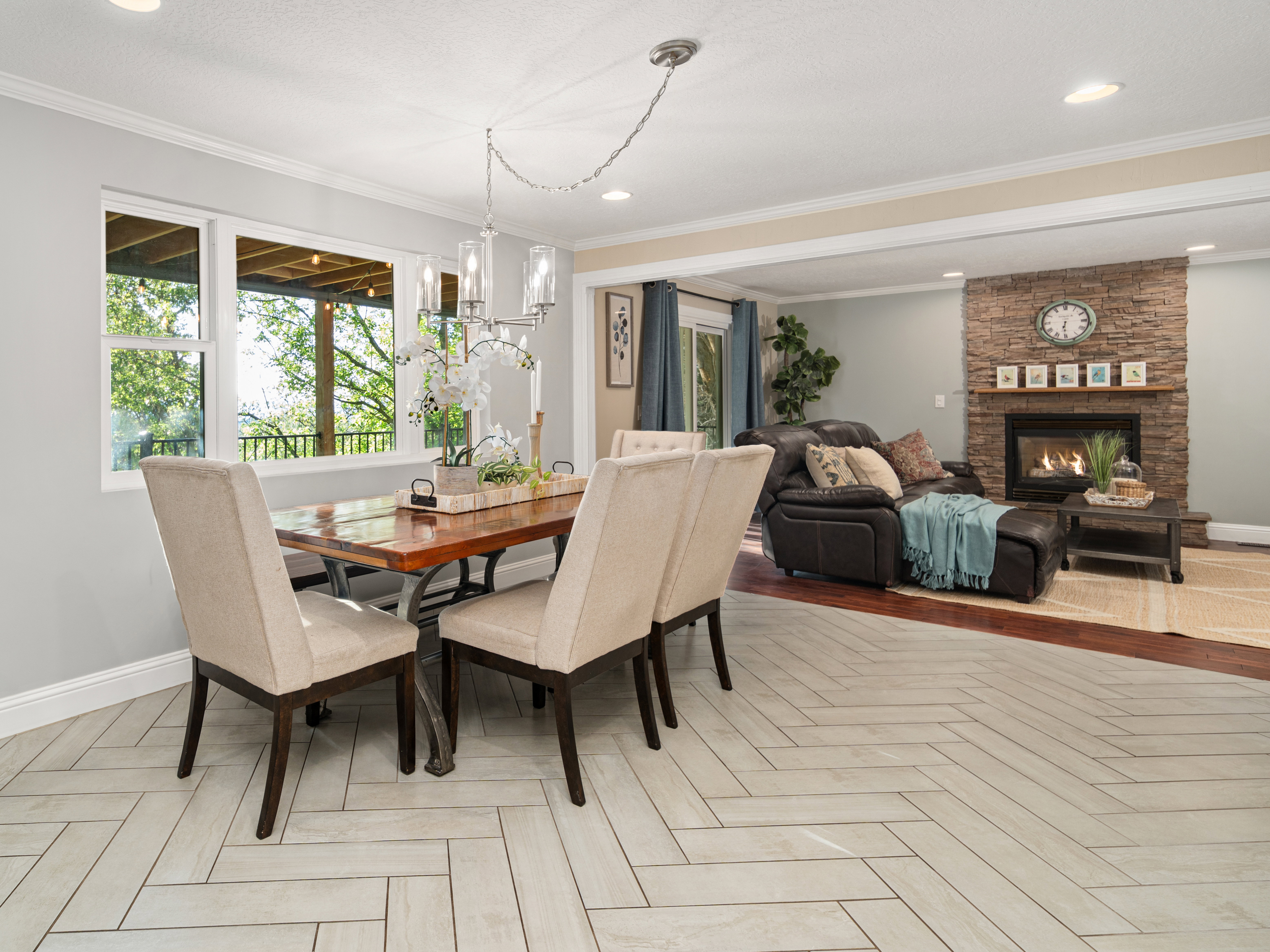Dining area featuring wood-finish flooring in a herringbone pattern, a contemporary chandelier, and large windows