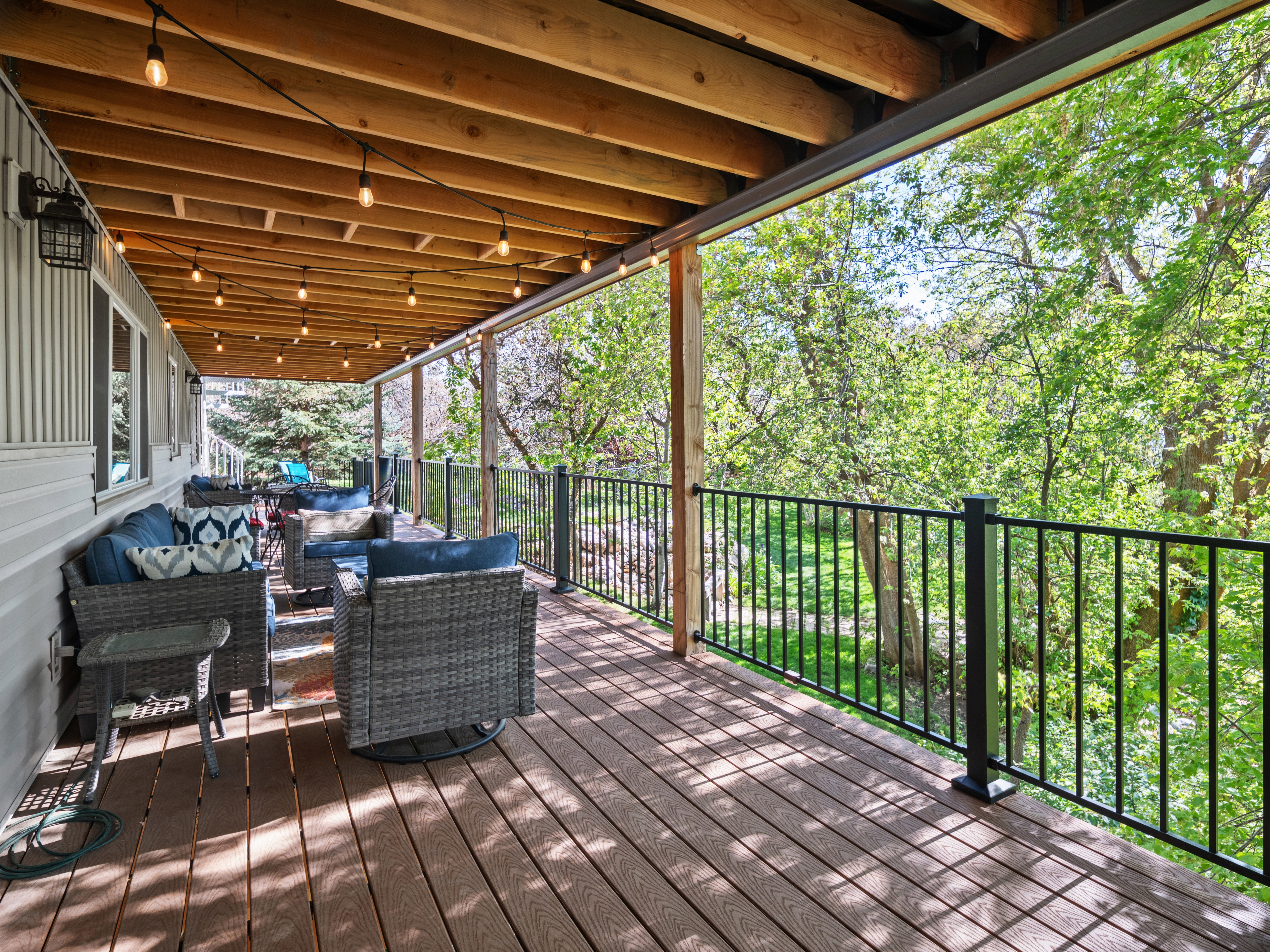 Expansive covered deck featuring wood-finish flooring and a black metal railing