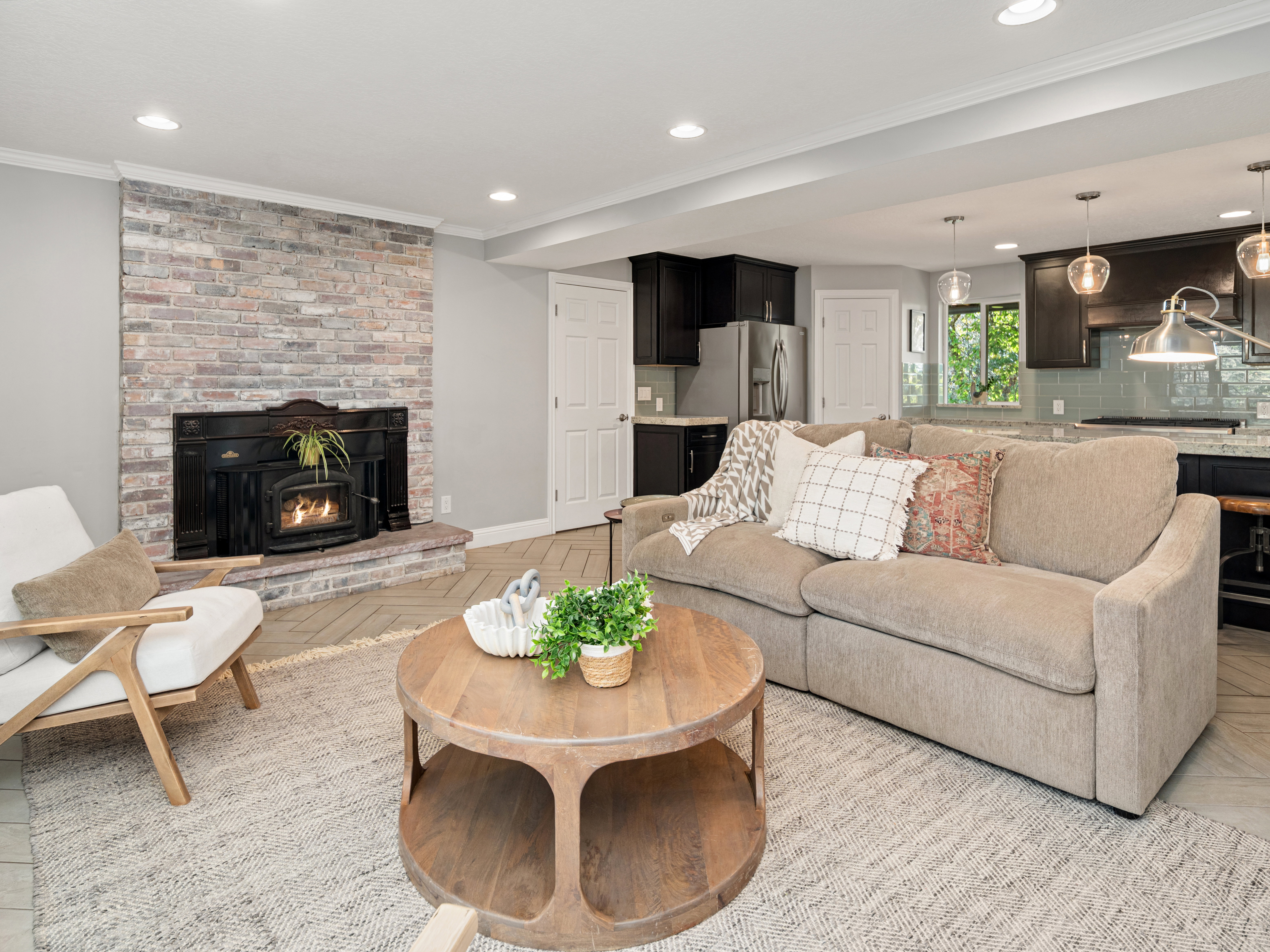 Open-concept living space featuring a brick fireplace with an insert, recessed lighting, and a wood-finish flooring