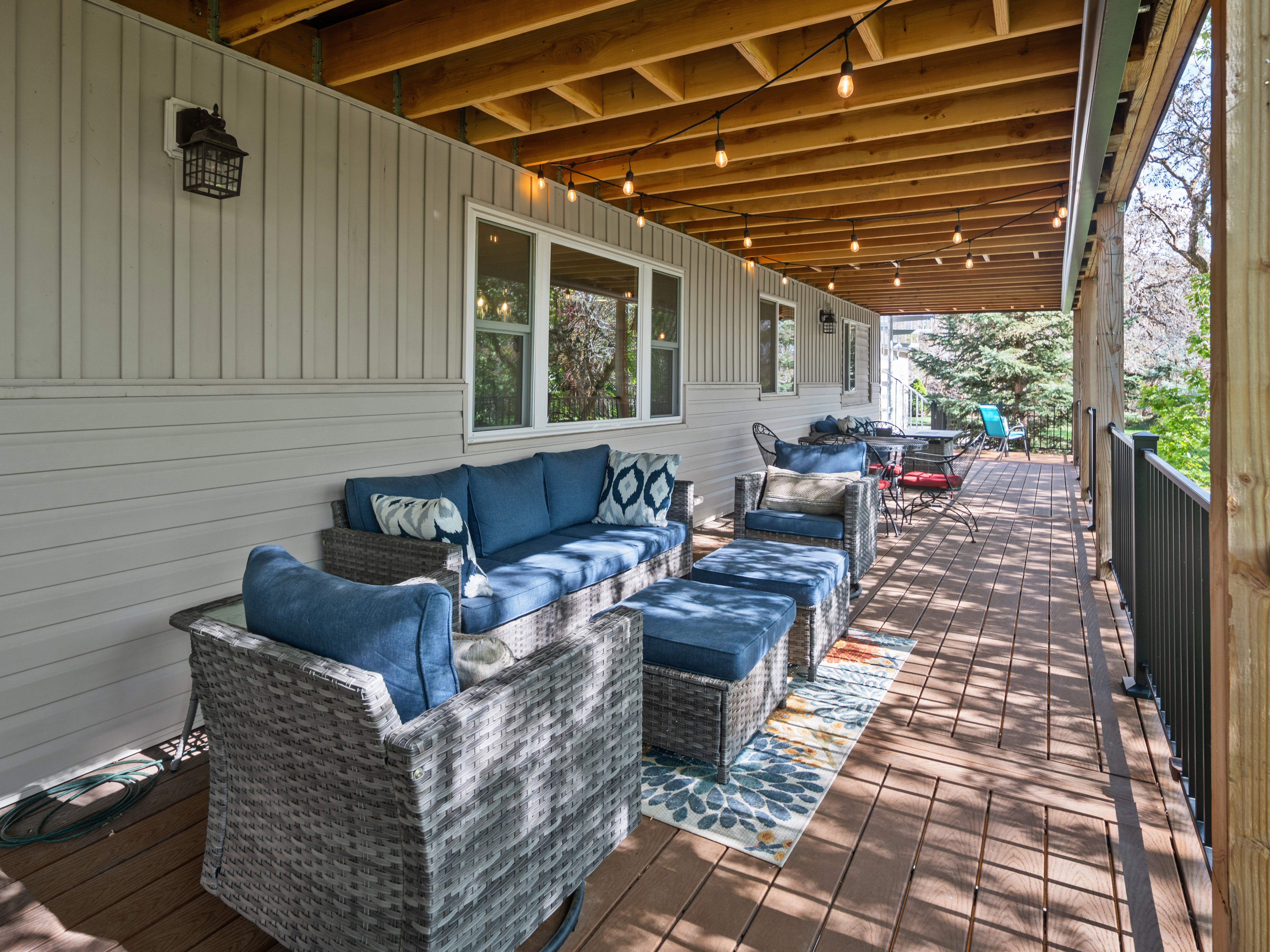 Expansive covered deck featuring wood-finish flooring, light-toned vertical siding, and multiple windows