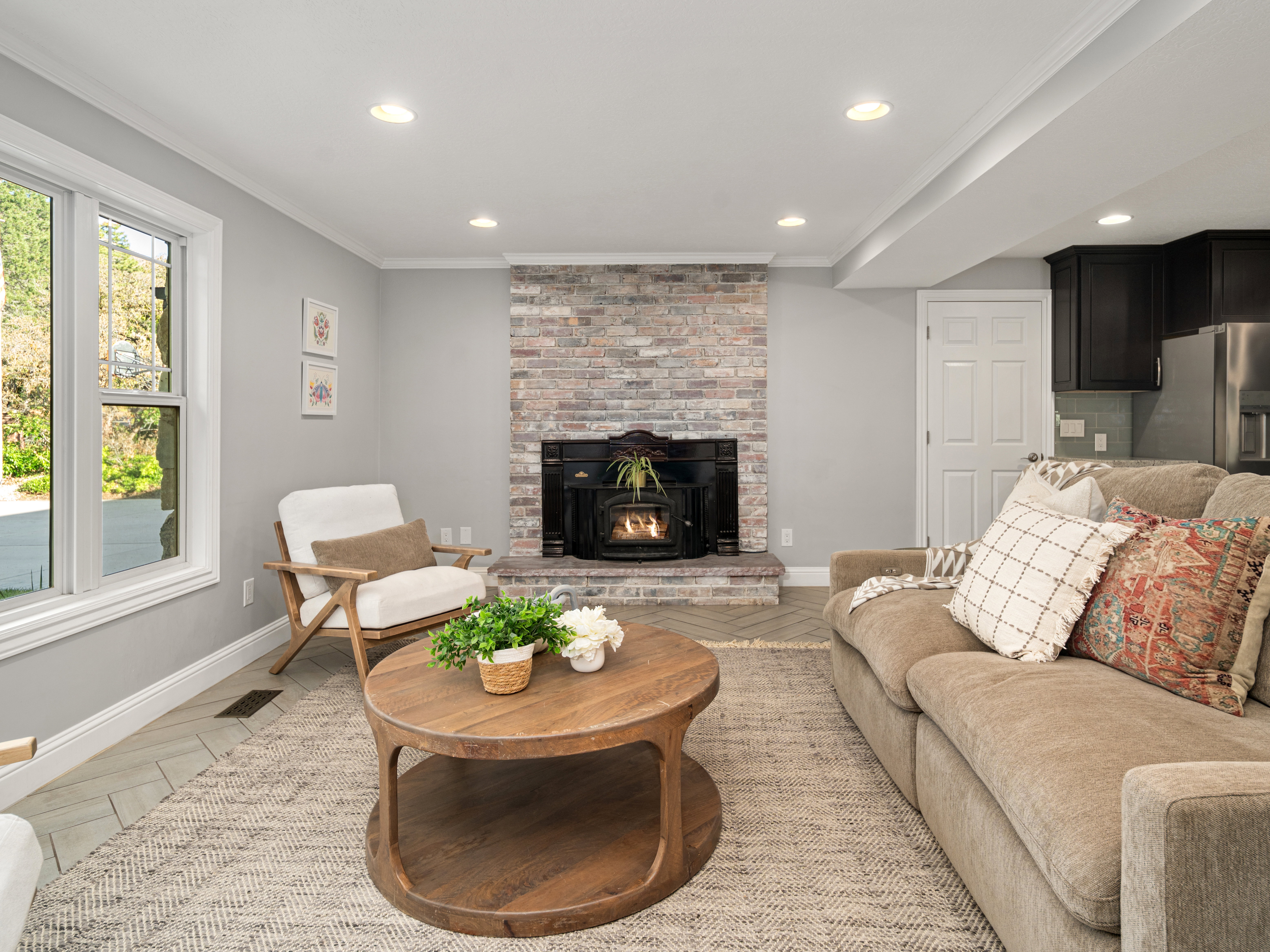 Living area with a stone-clad fireplace and insert, recessed lighting, and wood-finish flooring laid in a herringbone pattern