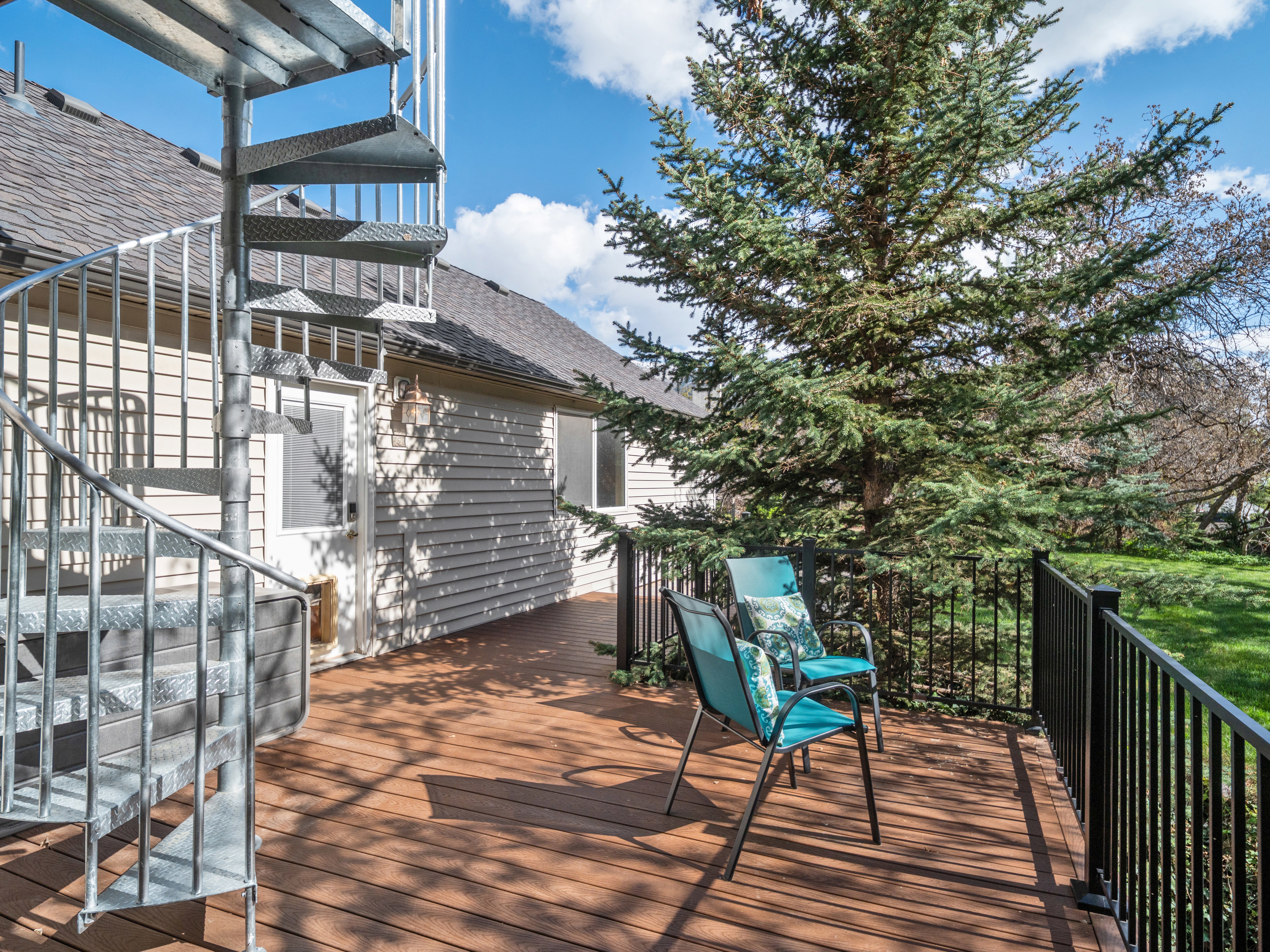 Expansive brown wood-finish deck featuring a metal spiral staircase and black metal railings