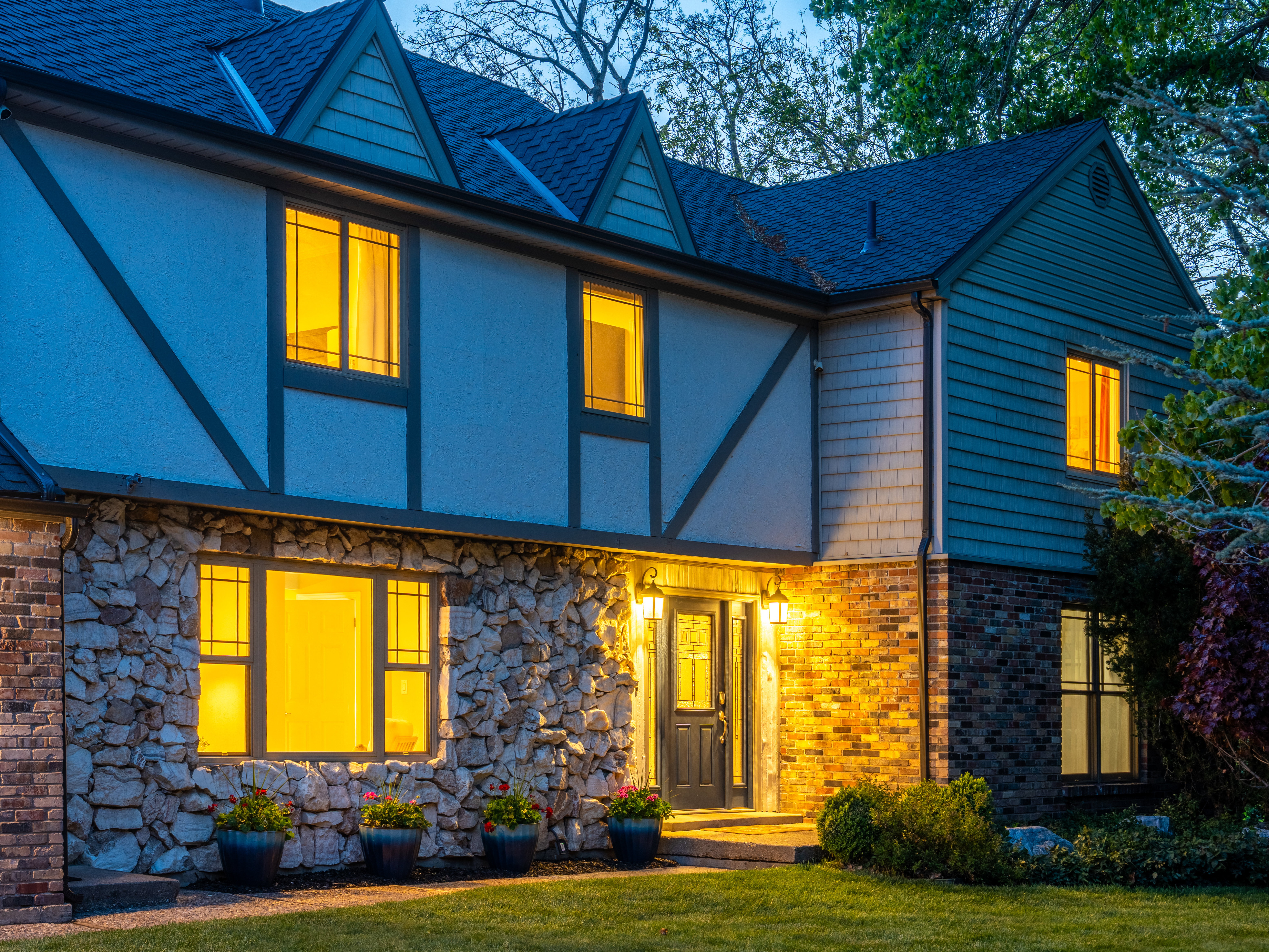 Tudor-style facade featuring stone and brick accents, decorative half-timbering, and shingle siding