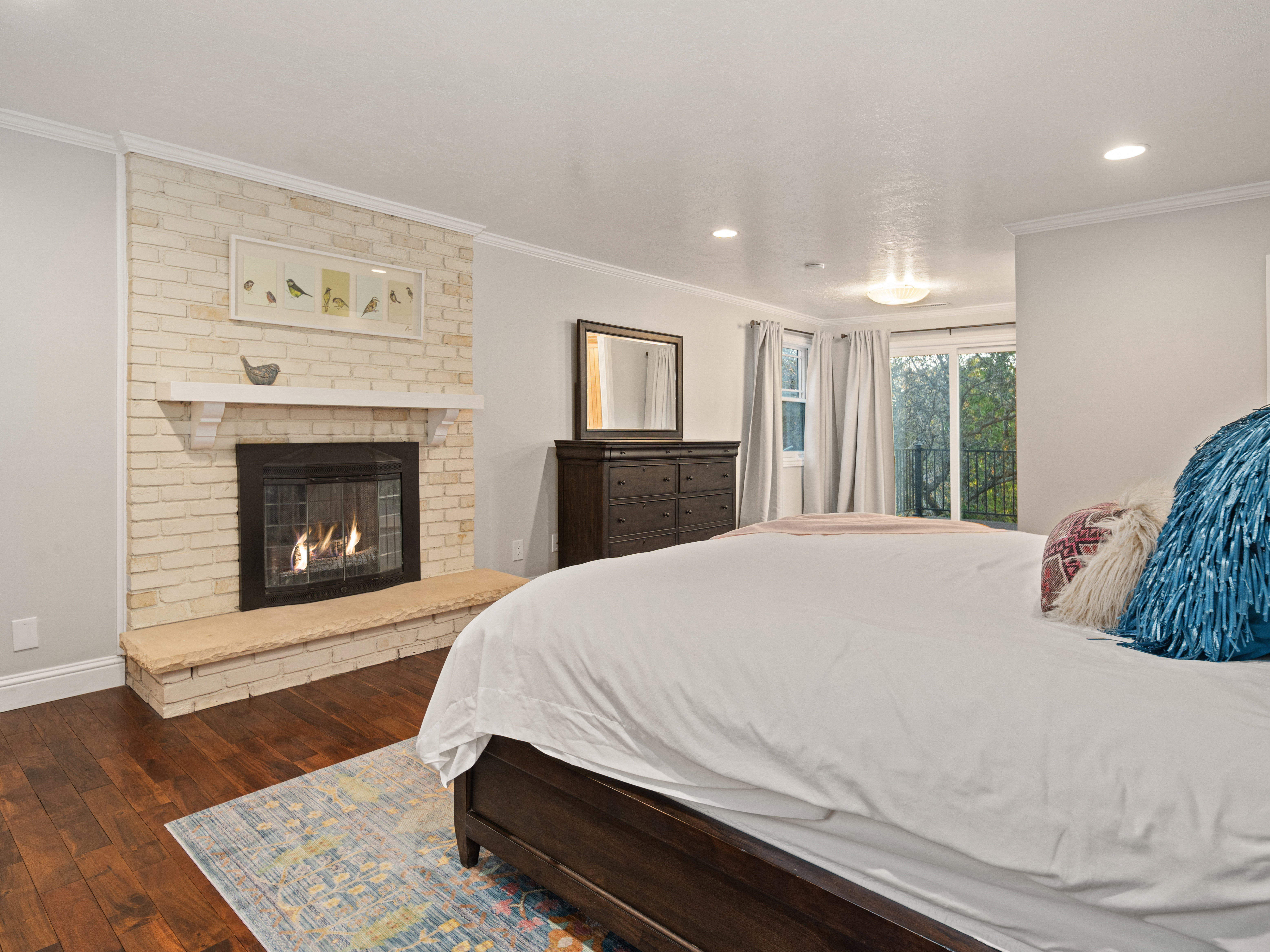 Bedroom featuring a brick-faced fireplace with a stone hearth, wood-finish flooring, and a sliding glass door opening to an outdoor area