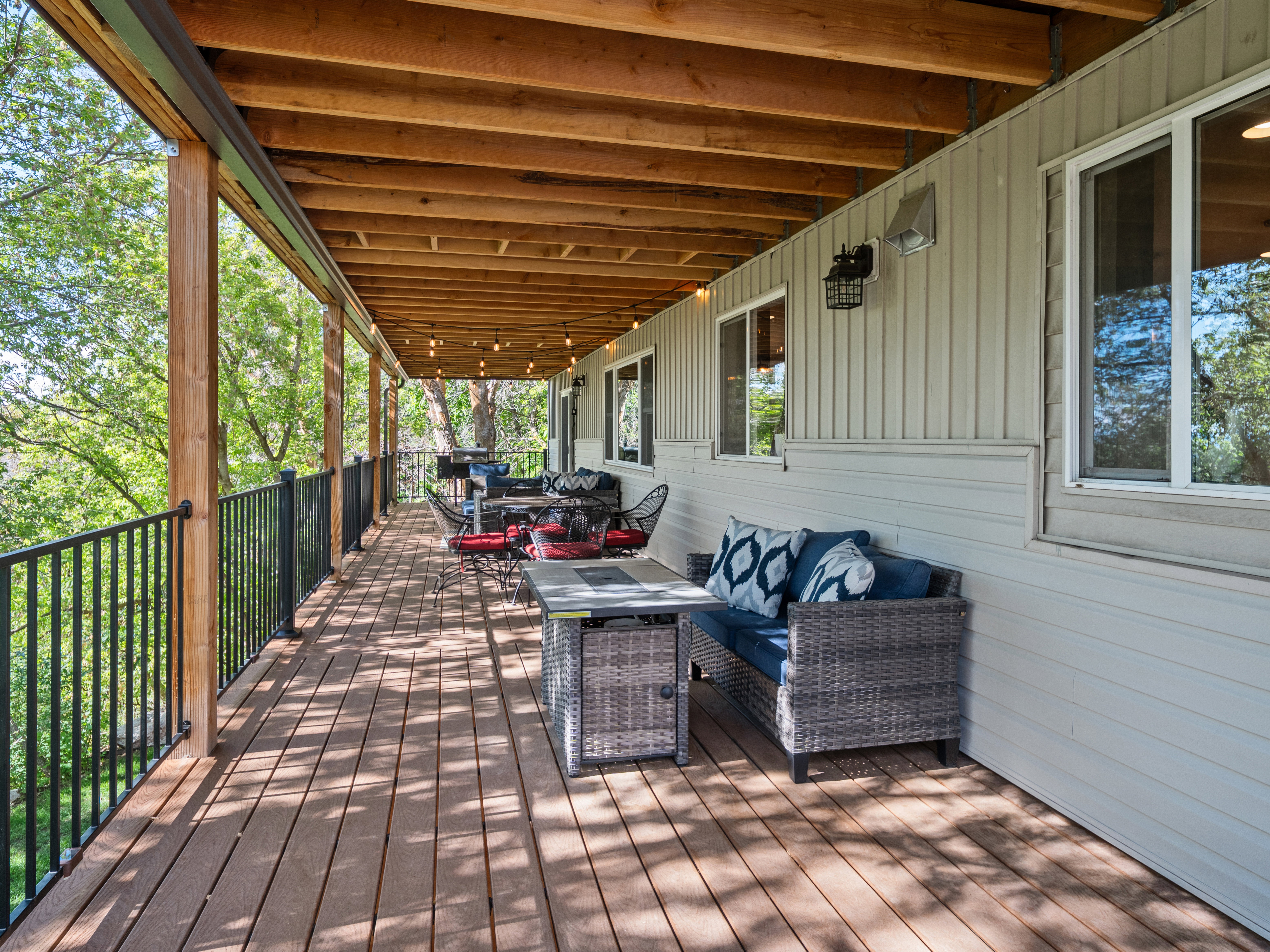 Expansive covered deck featuring wood-finish flooring, exposed wood beams, and black metal railings