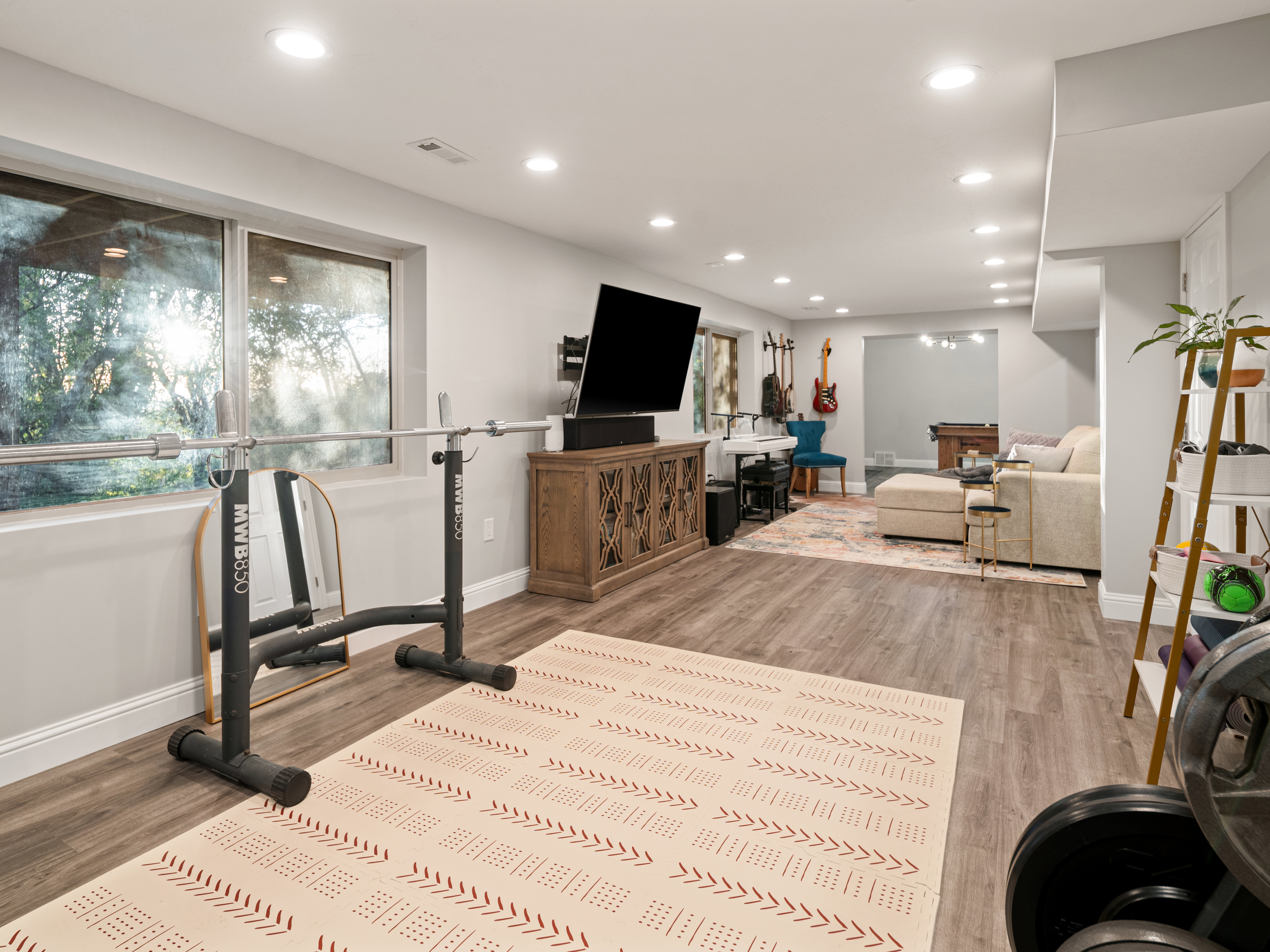 Spacious lower-level area with wood-finish flooring, recessed lighting, and large windows
