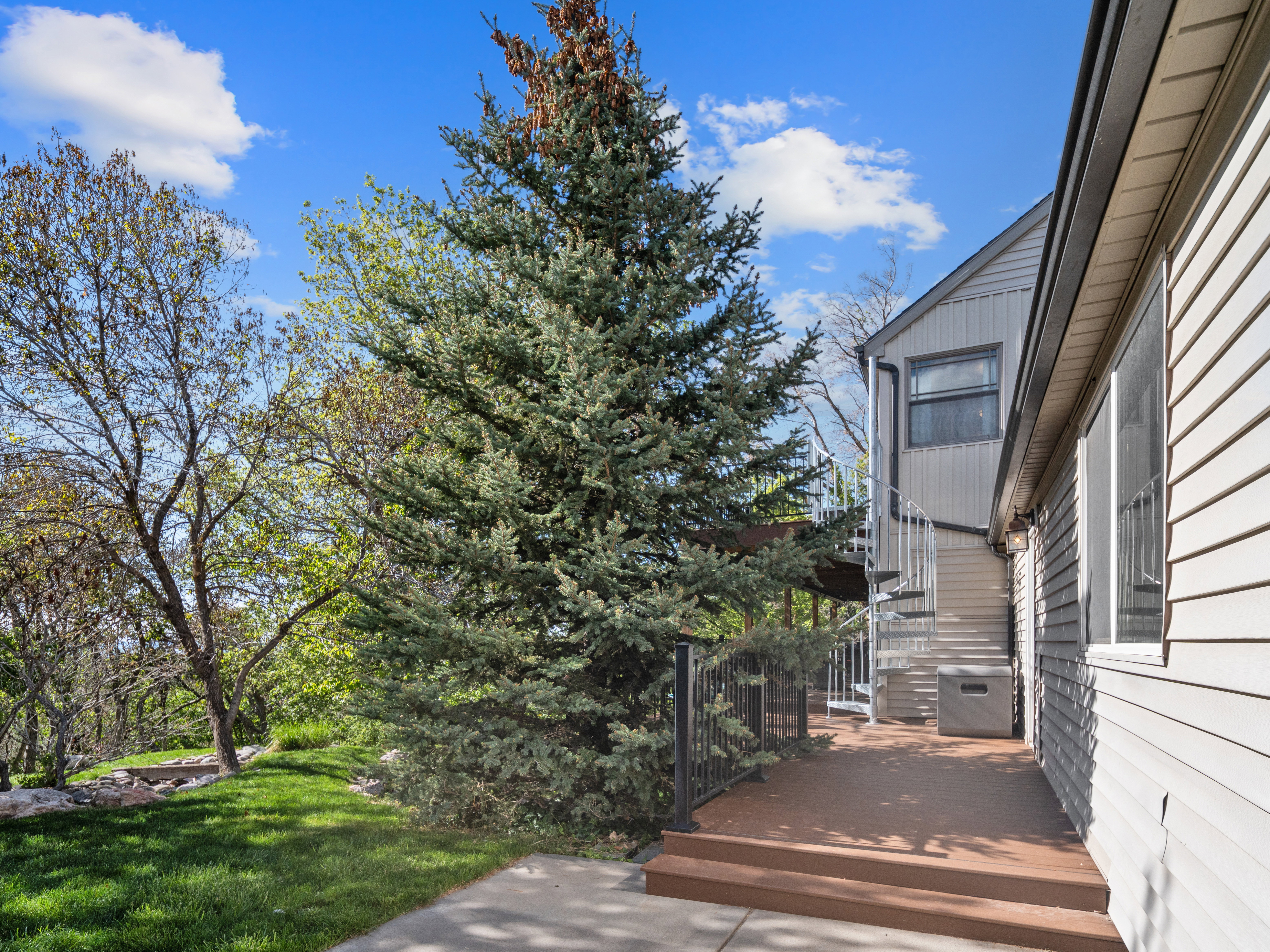 Expansive multi-level deck featuring a spiral staircase, metal railings, and a built-in outdoor storage unit