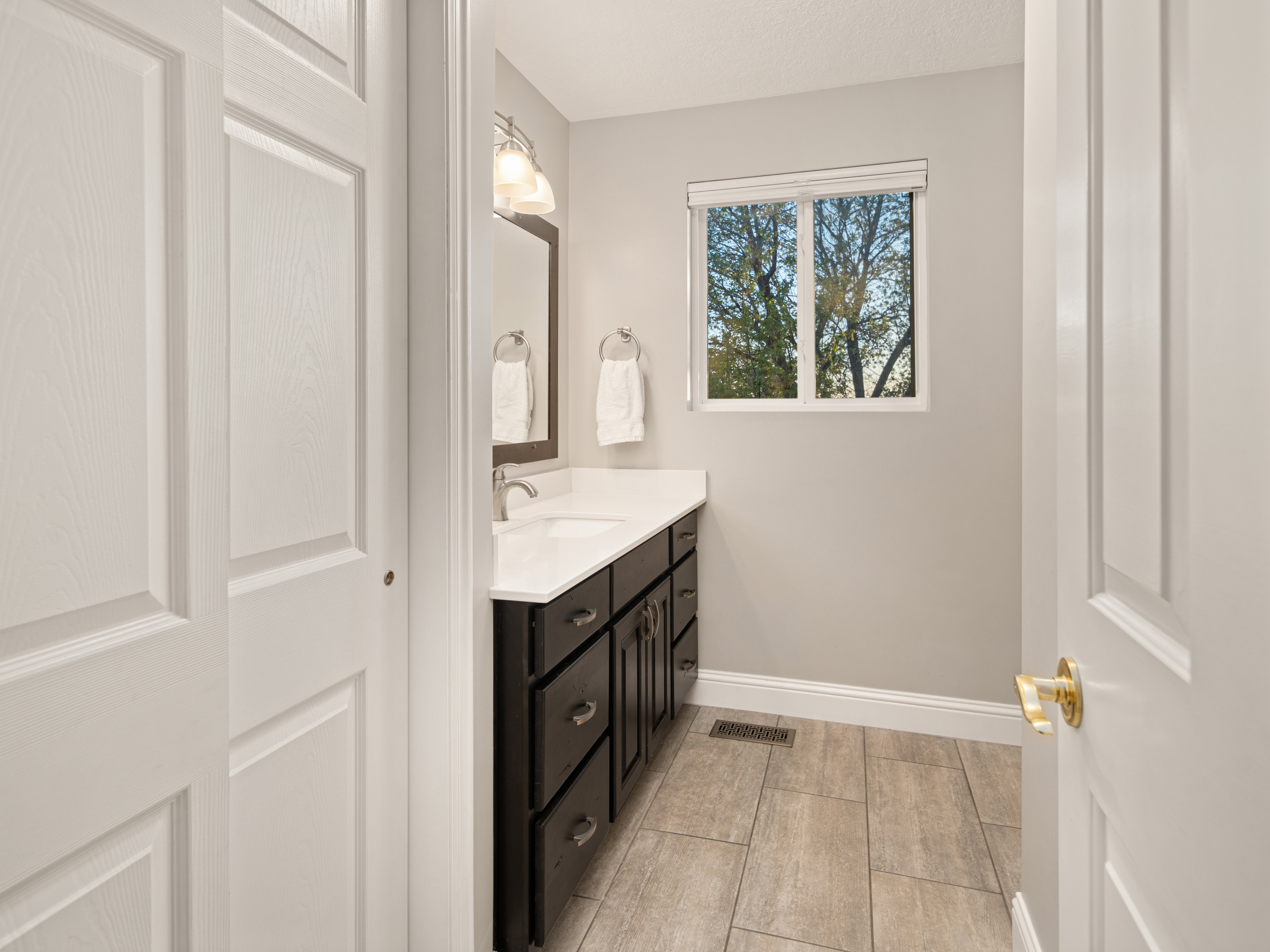 Bathroom featuring a dark wood-finish vanity with a white countertop and undermount sink, brushed nickel faucet, and overhead light fixture