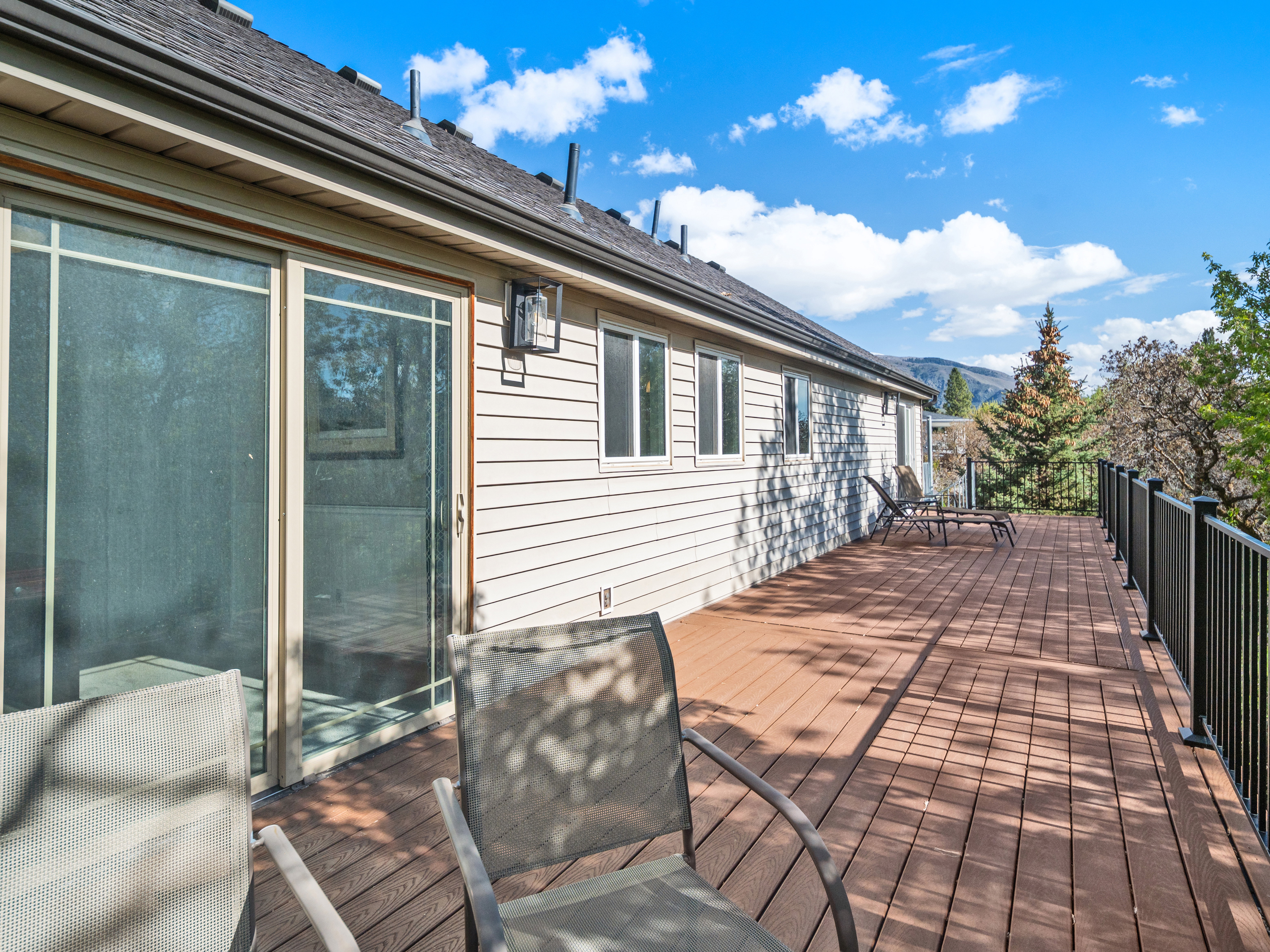 Expansive outdoor deck featuring wood-finish flooring, black metal railings, and siding exterior