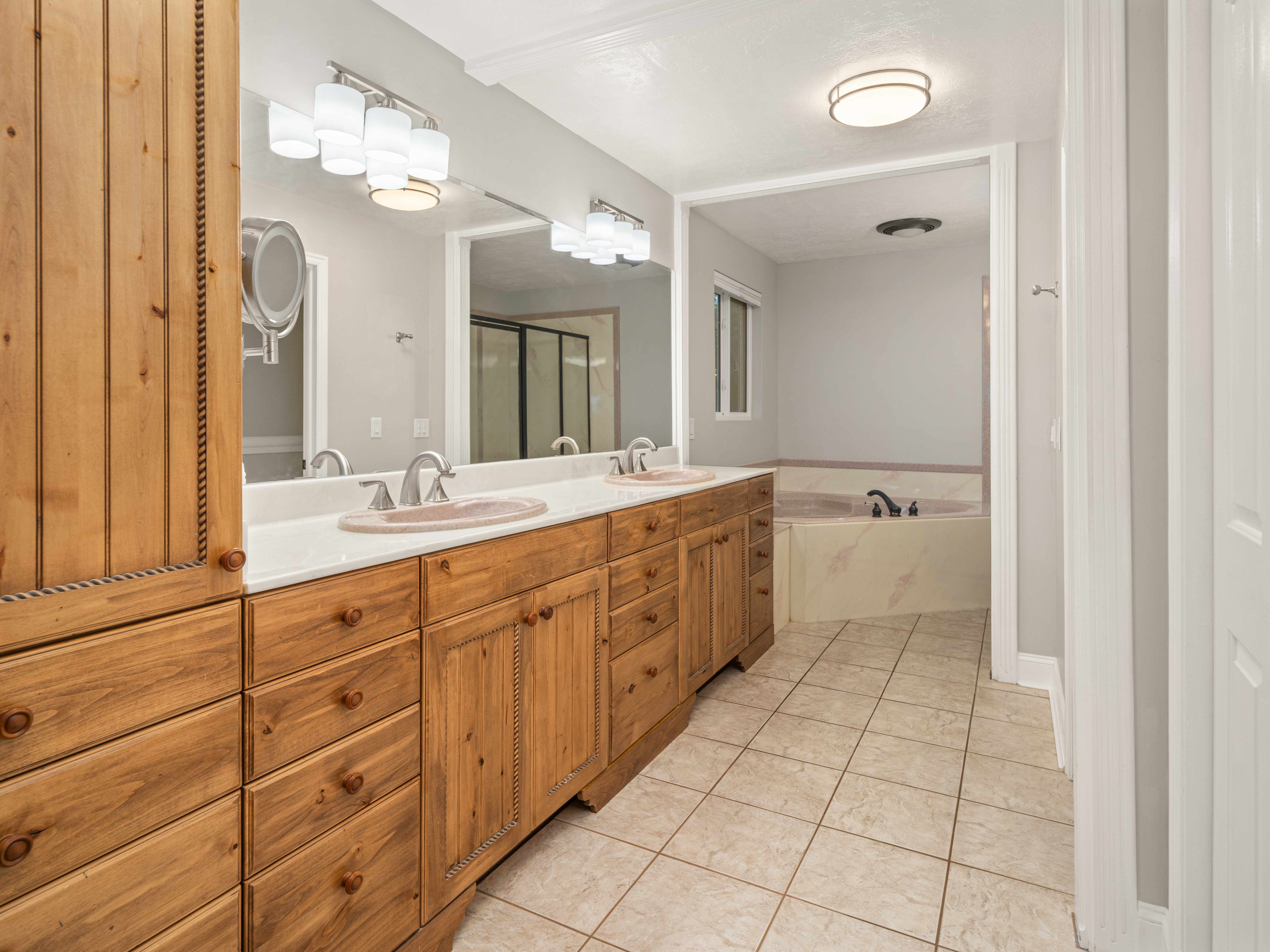 Bathroom featuring a dual vanity with light wood cabinetry, a white countertop, and integrated sinks