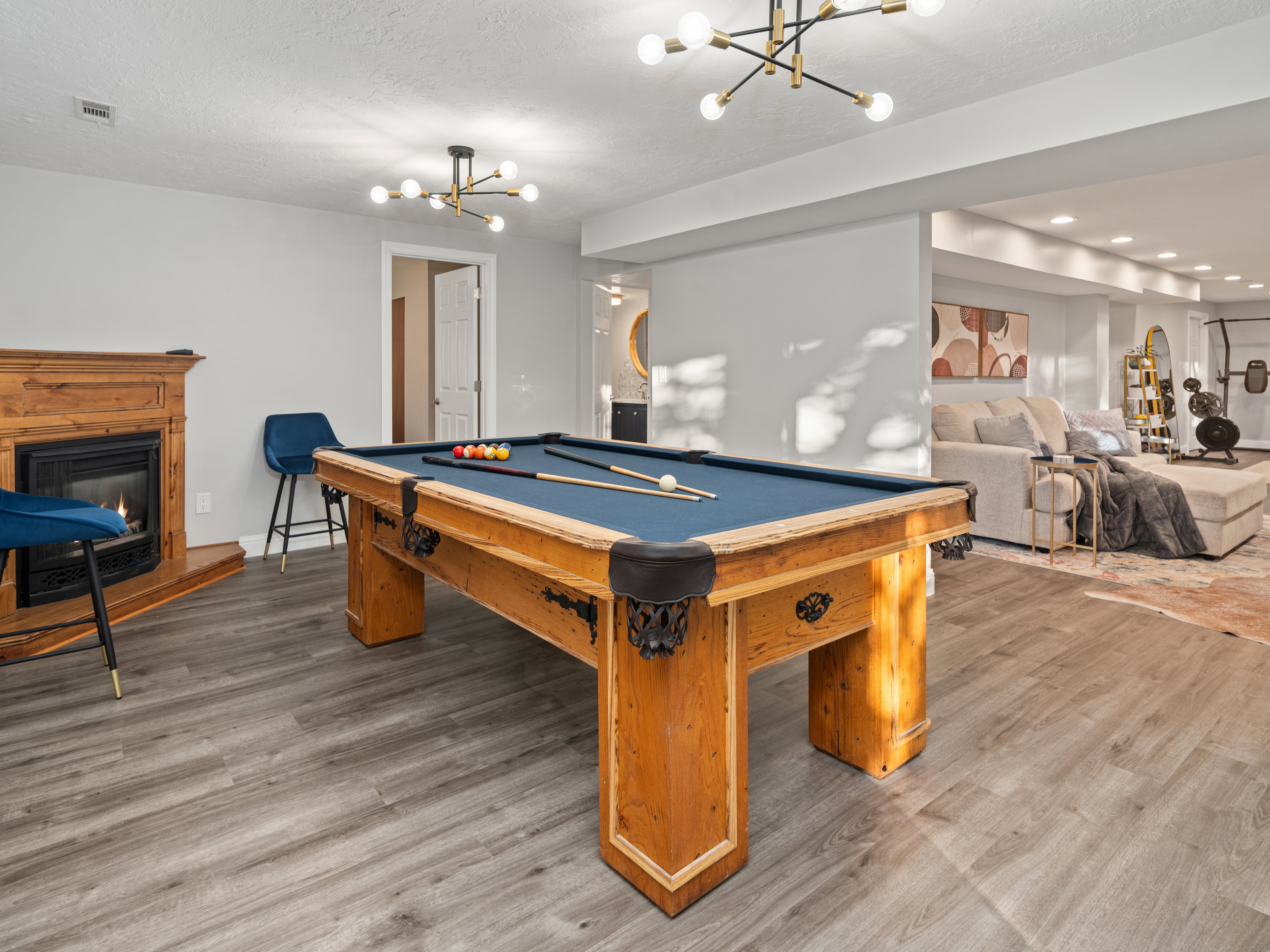 Recreation room featuring a pool table, wood-finish flooring, and a fireplace with a wood mantle