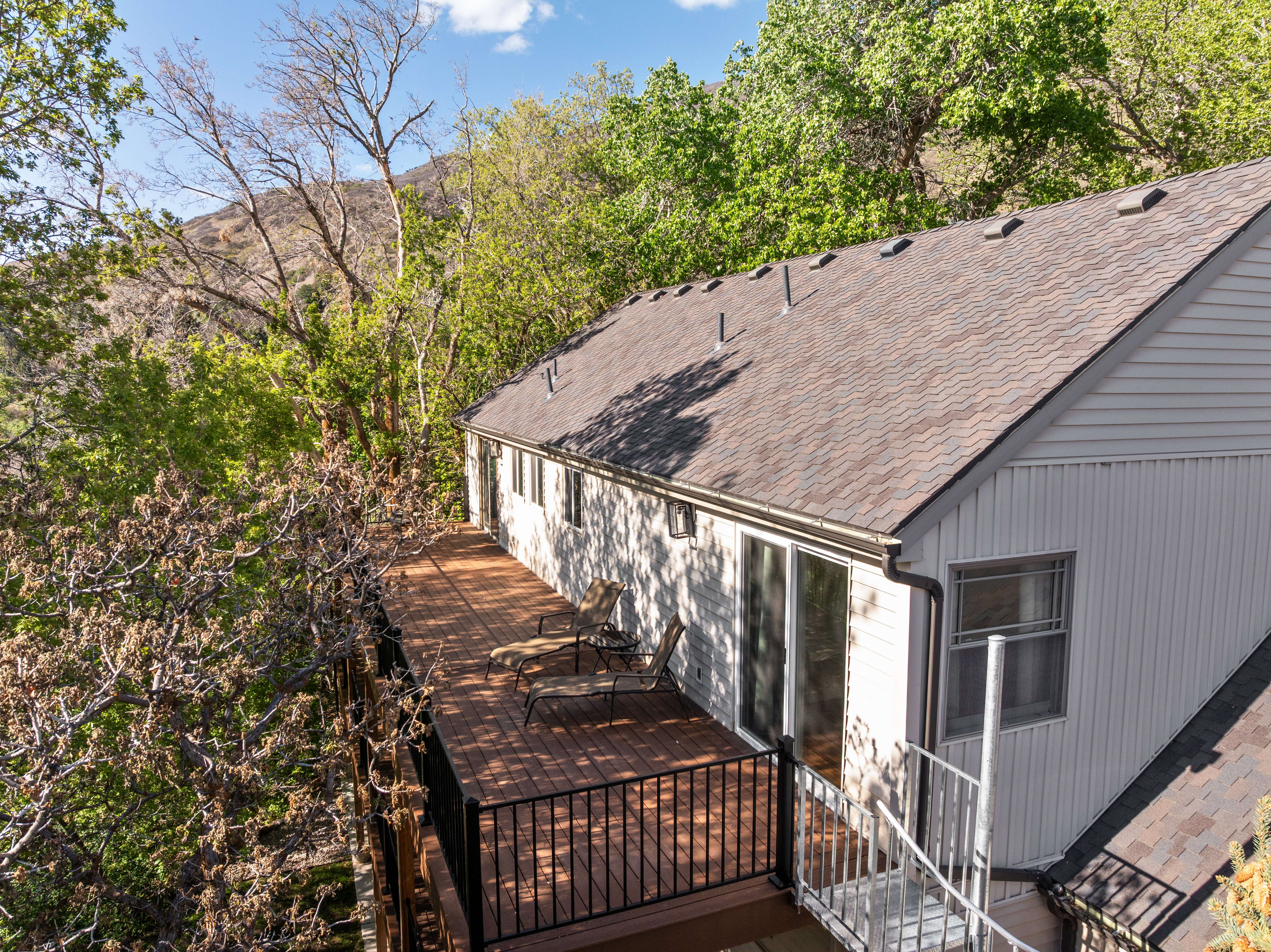 Expansive wood-finish deck with black metal railings, accessible via sliding glass doors