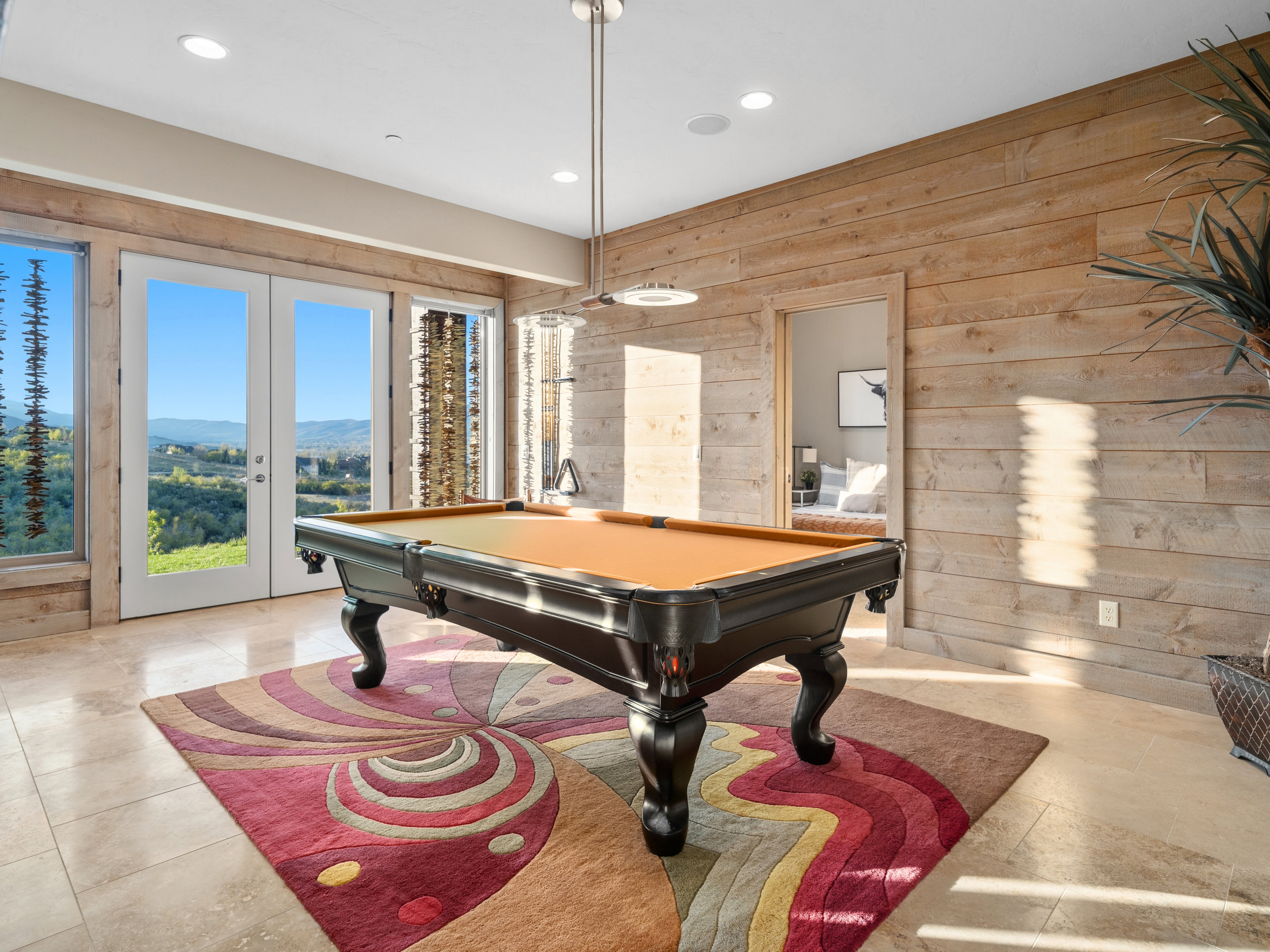 Recreational space featuring a billiards table, expansive windows, glass-paneled French doors, wood-finish accent wall, and recessed lighting