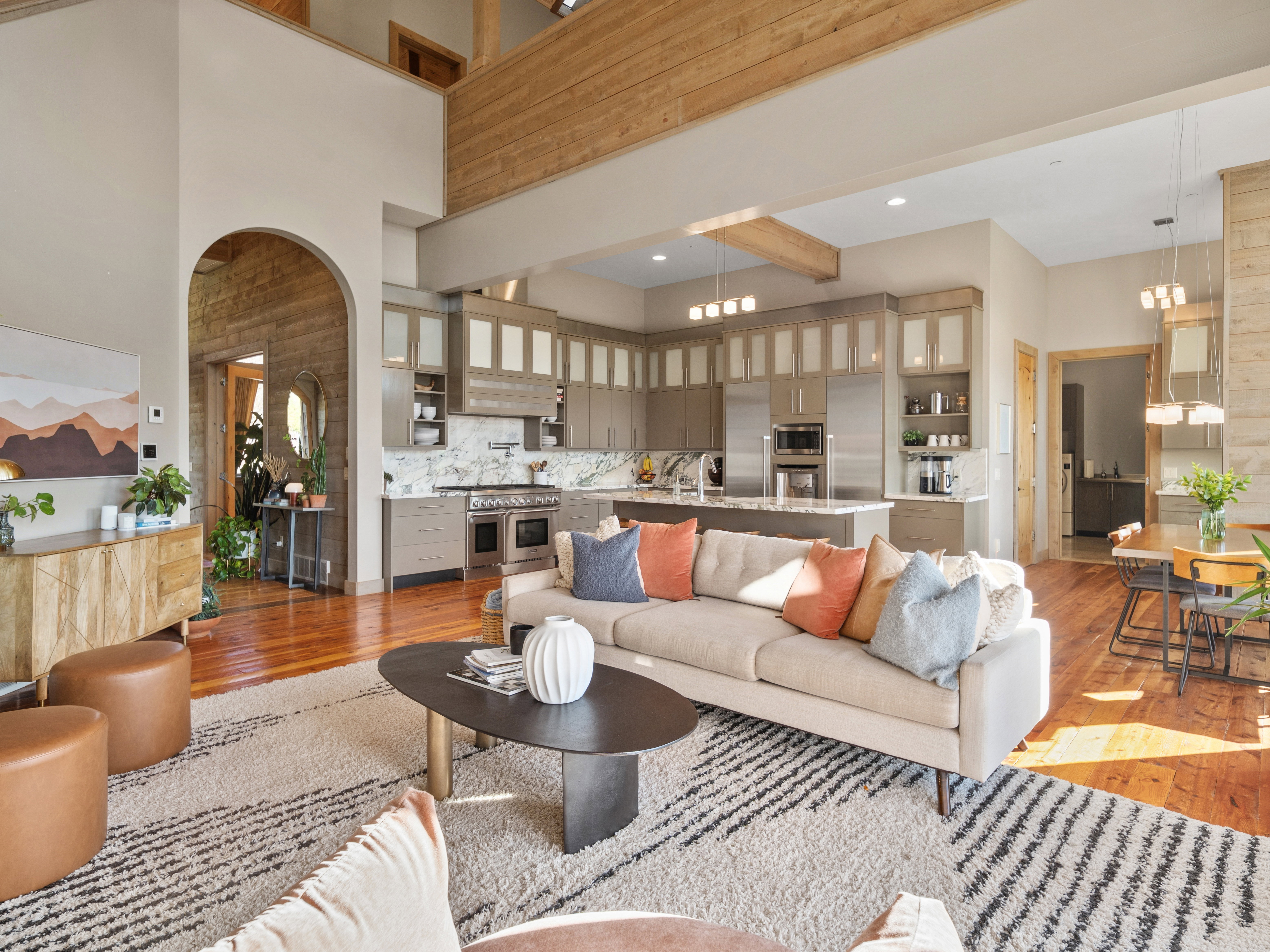 Open-concept living space featuring a gourmet kitchen with stainless steel appliances, a large central island, and white marble backsplash