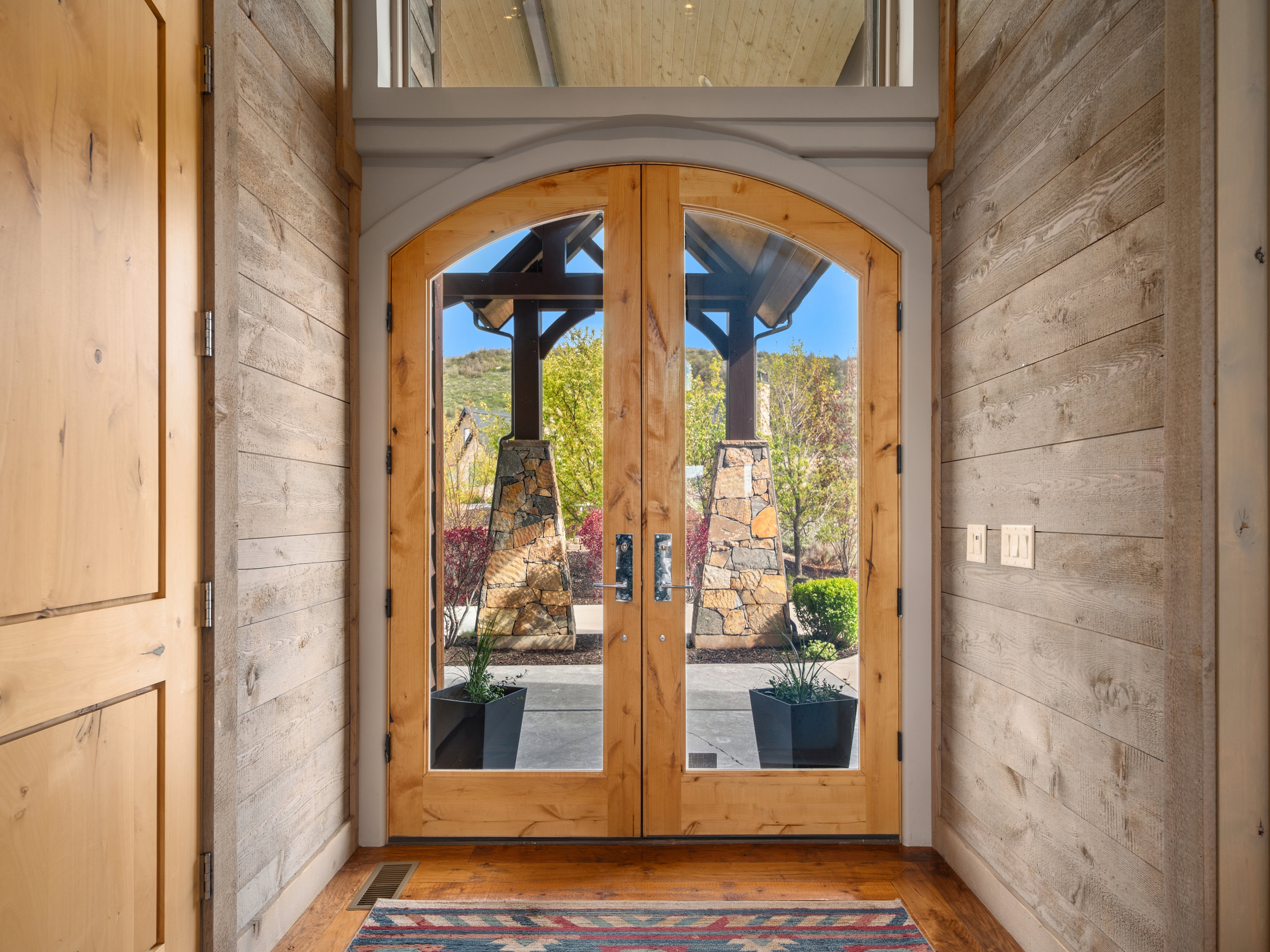 Arched double-door entryway with natural wood framing and clear glass panels