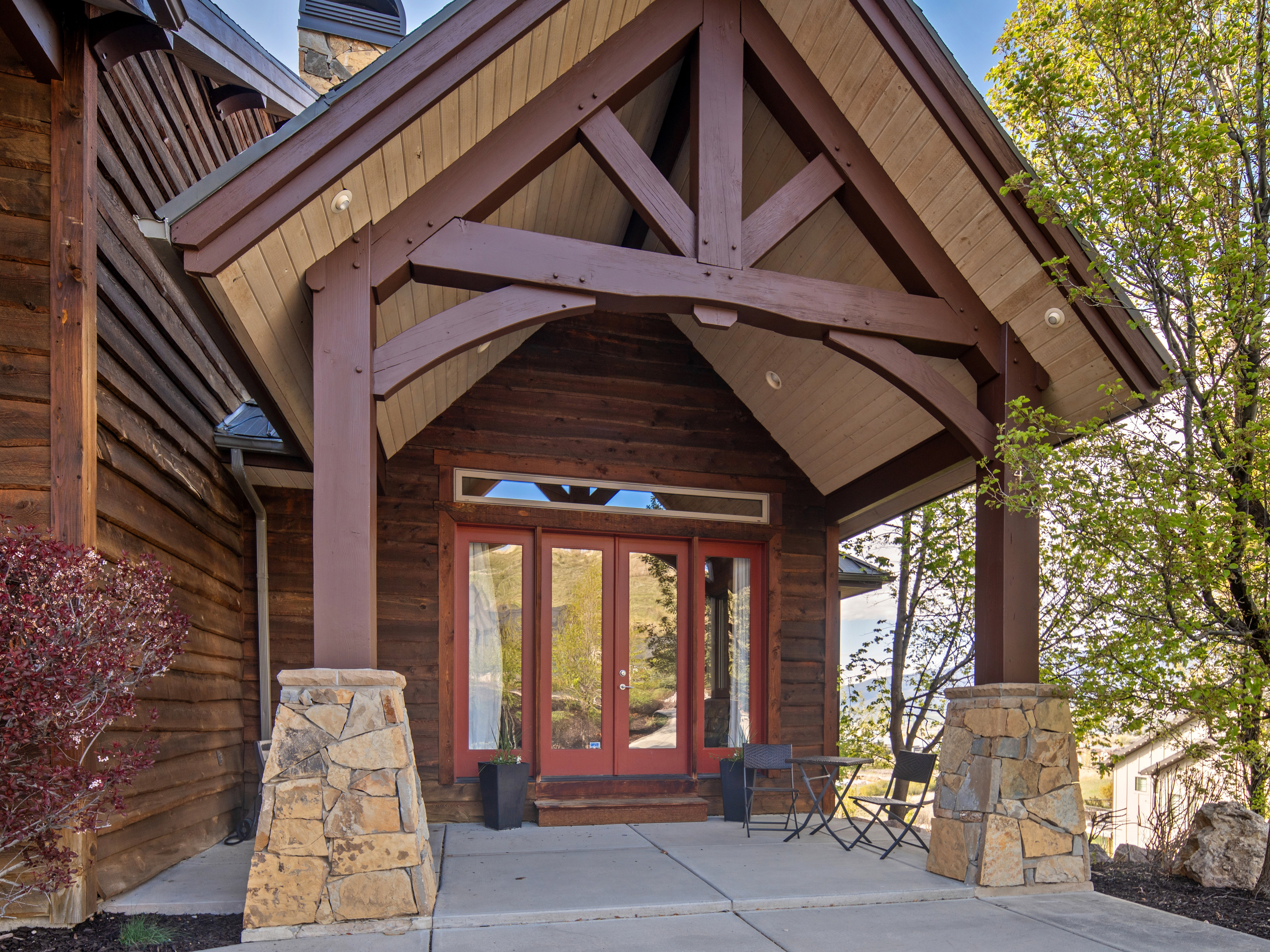 Rustic timber frame entry featuring a natural wood facade and stone-clad columns