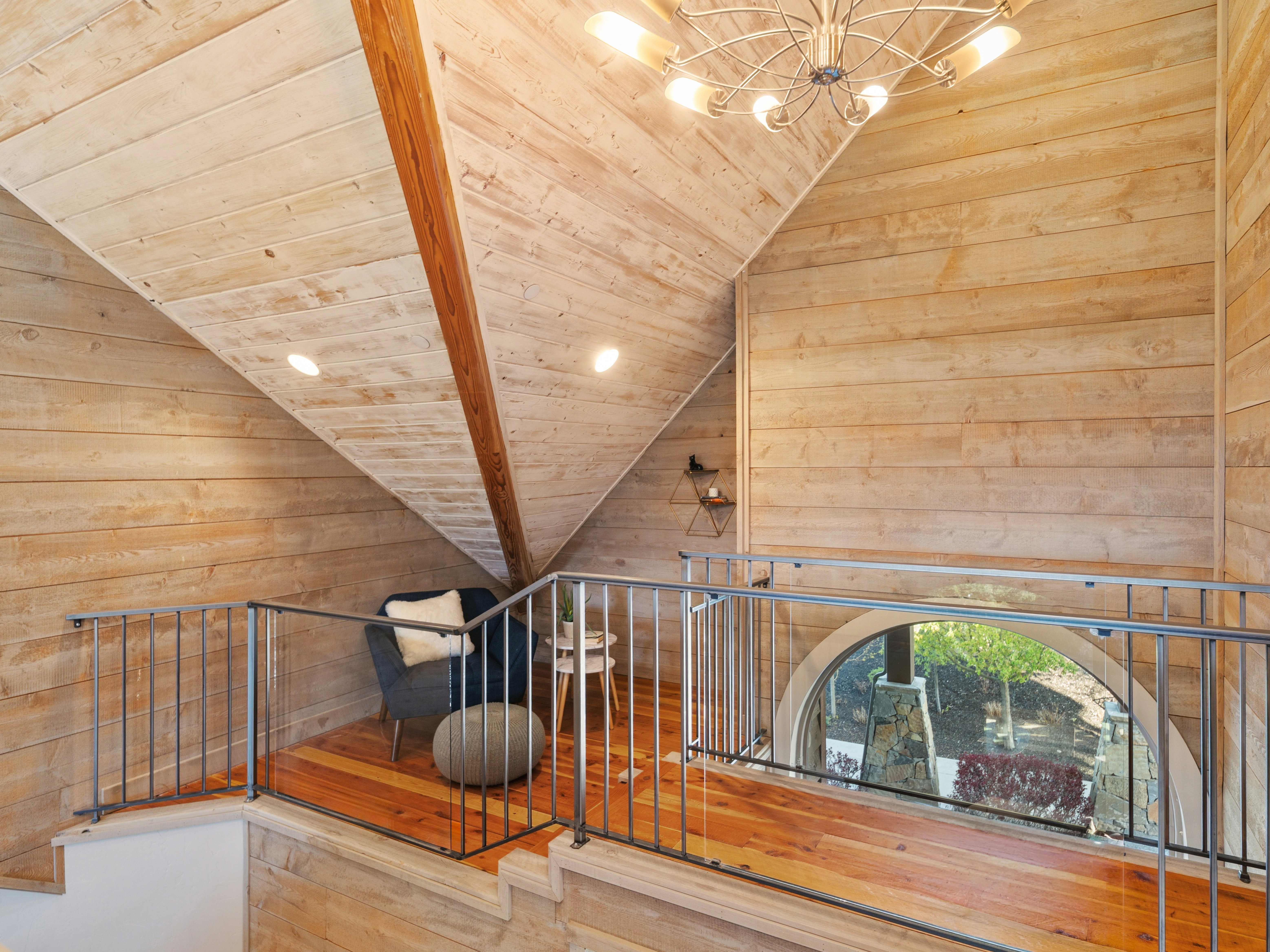 Loft space featuring extensive wood-finish wall and ceiling paneling, exposed wood beams, and recessed lighting
