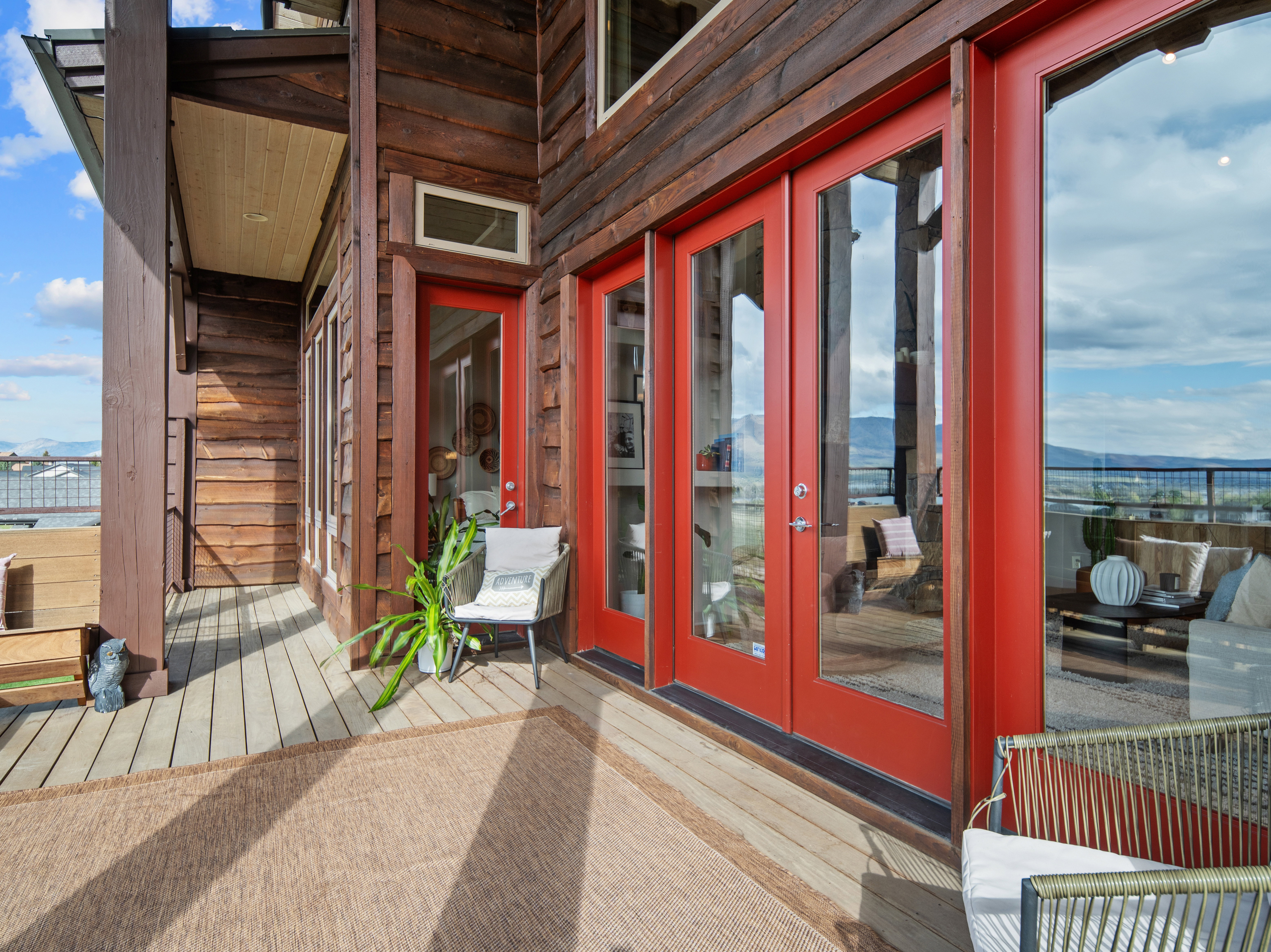 Expansive wood-finish deck with multiple red glass-paneled doors, wood siding, and an overhead wood-paneled soffit
