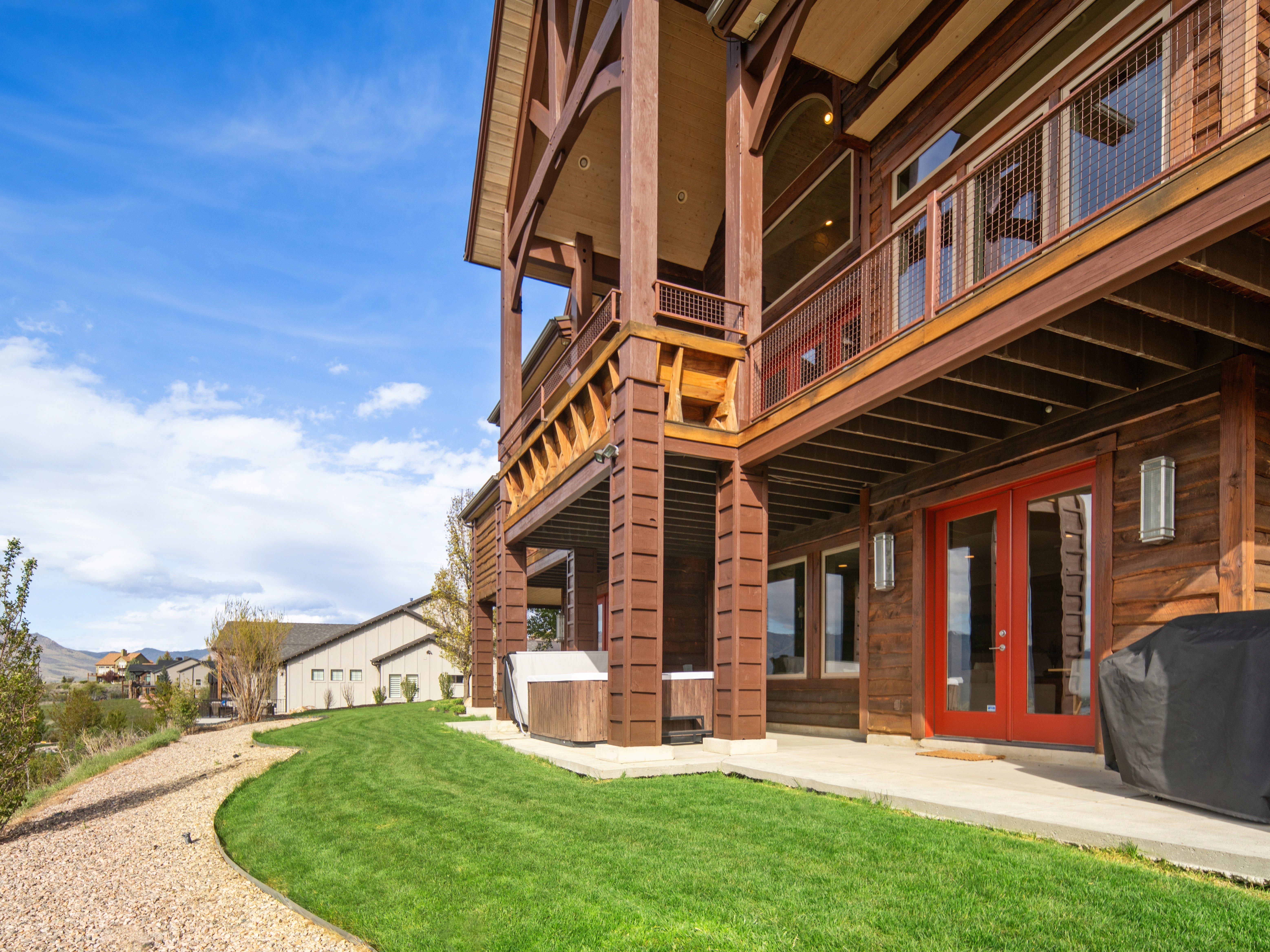 Multi-level wood-clad exterior featuring a ground-level patio, private balcony, and built-in spa