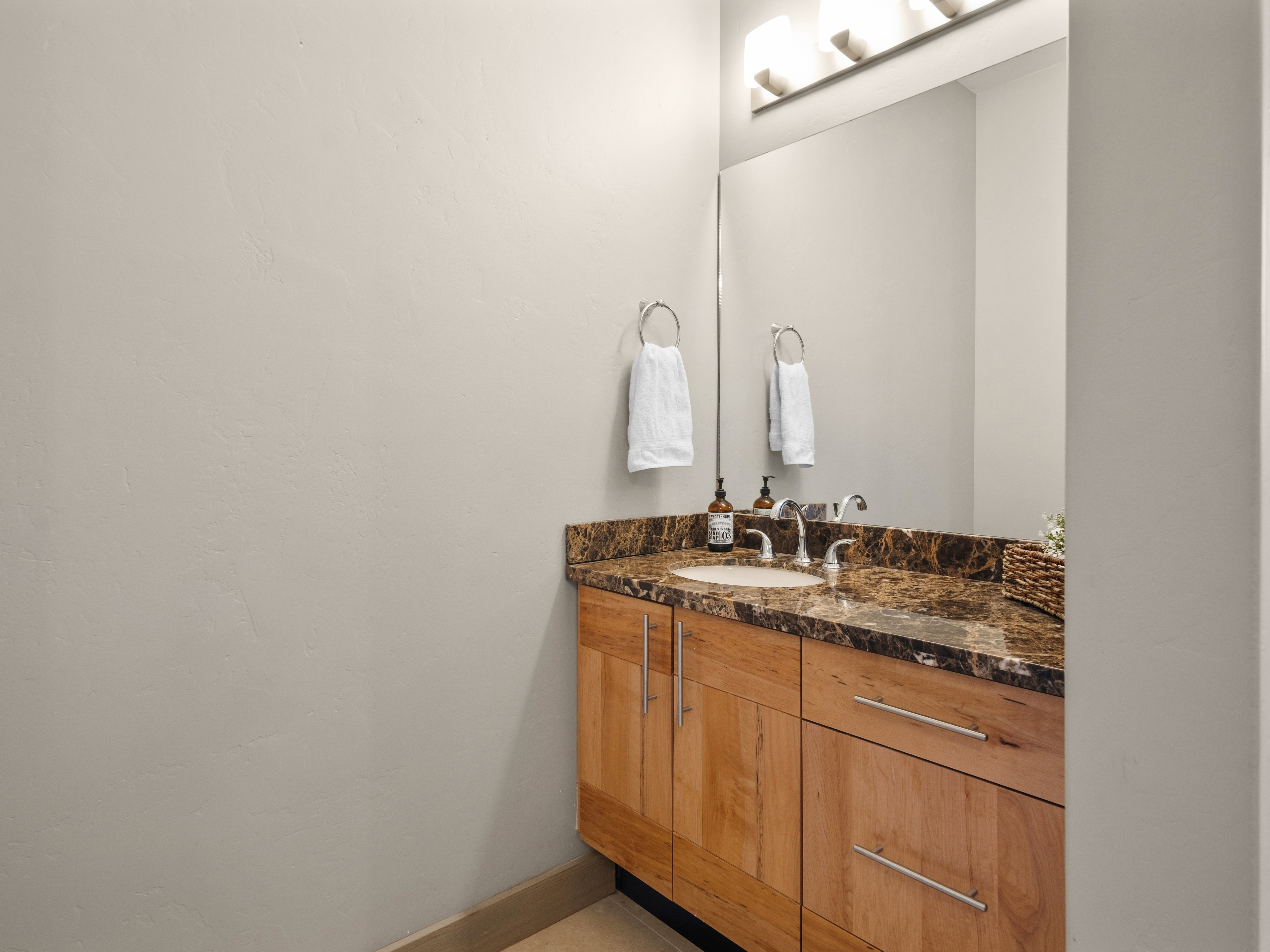 Vanity with a polished stone countertop, undermount sink, and chrome faucet