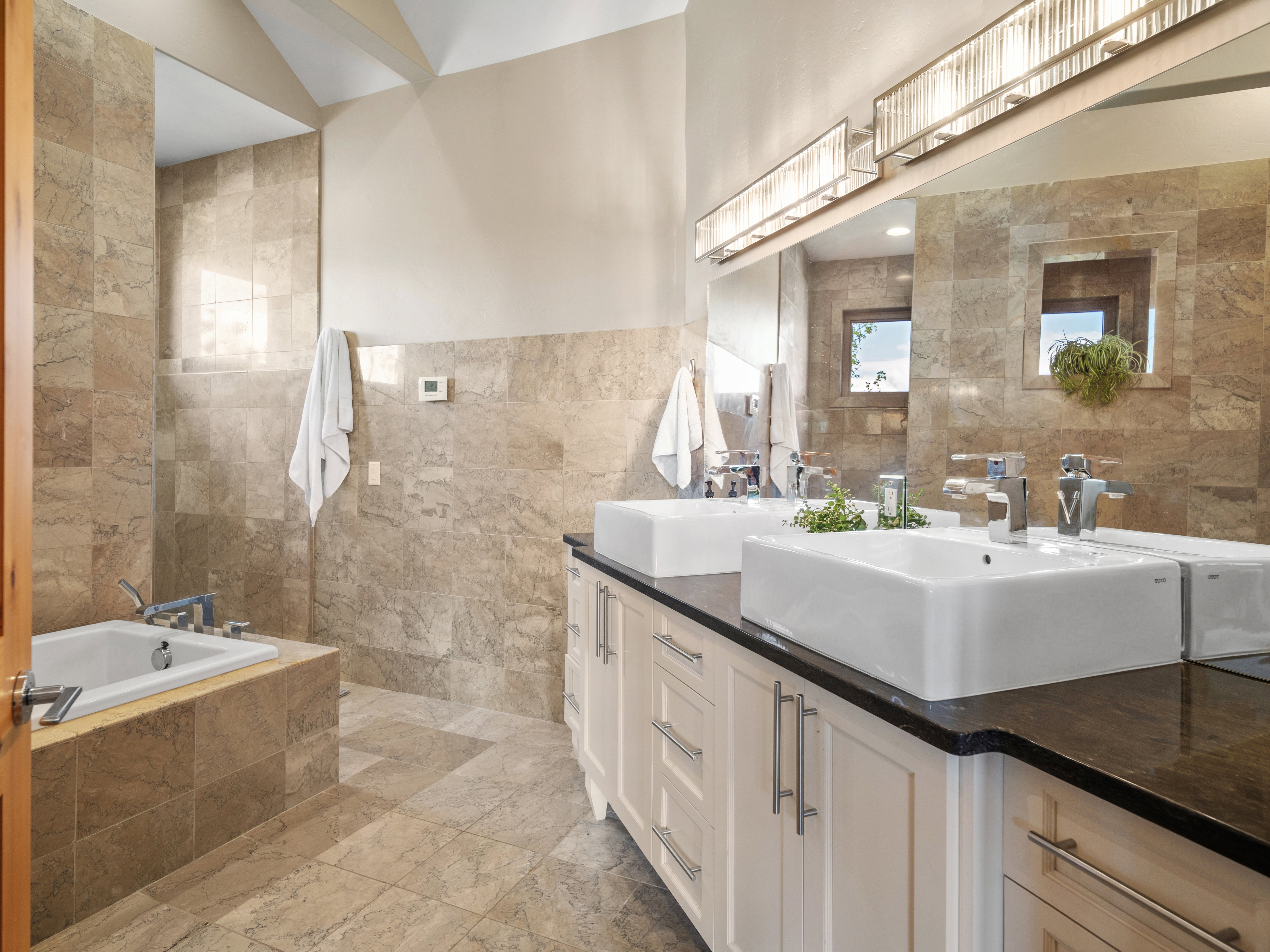 Spa-inspired bath featuring a tiled soaking tub and a double vanity with vessel sinks