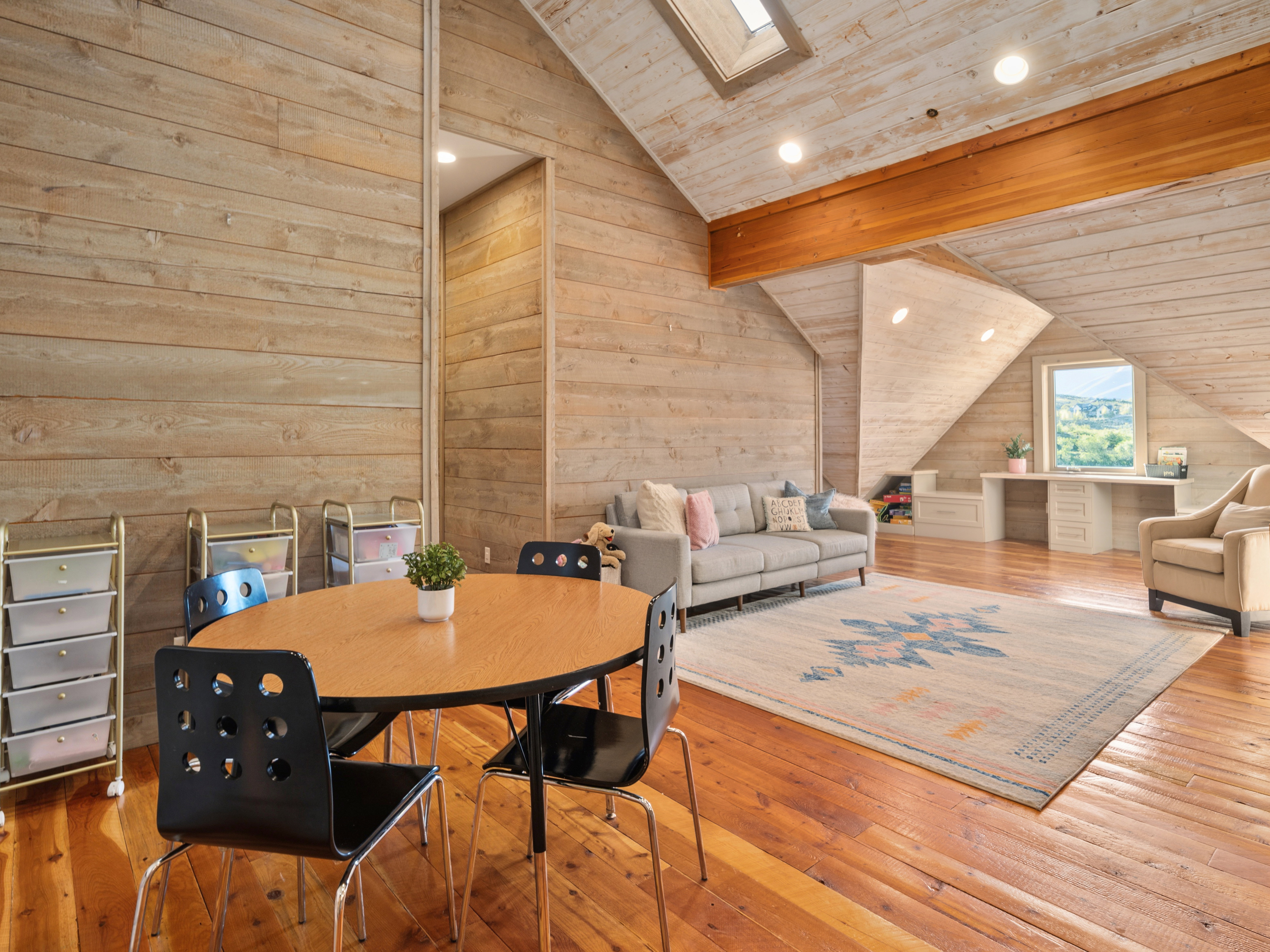 Spacious loft area featuring wood-finish flooring and plank-paneled walls