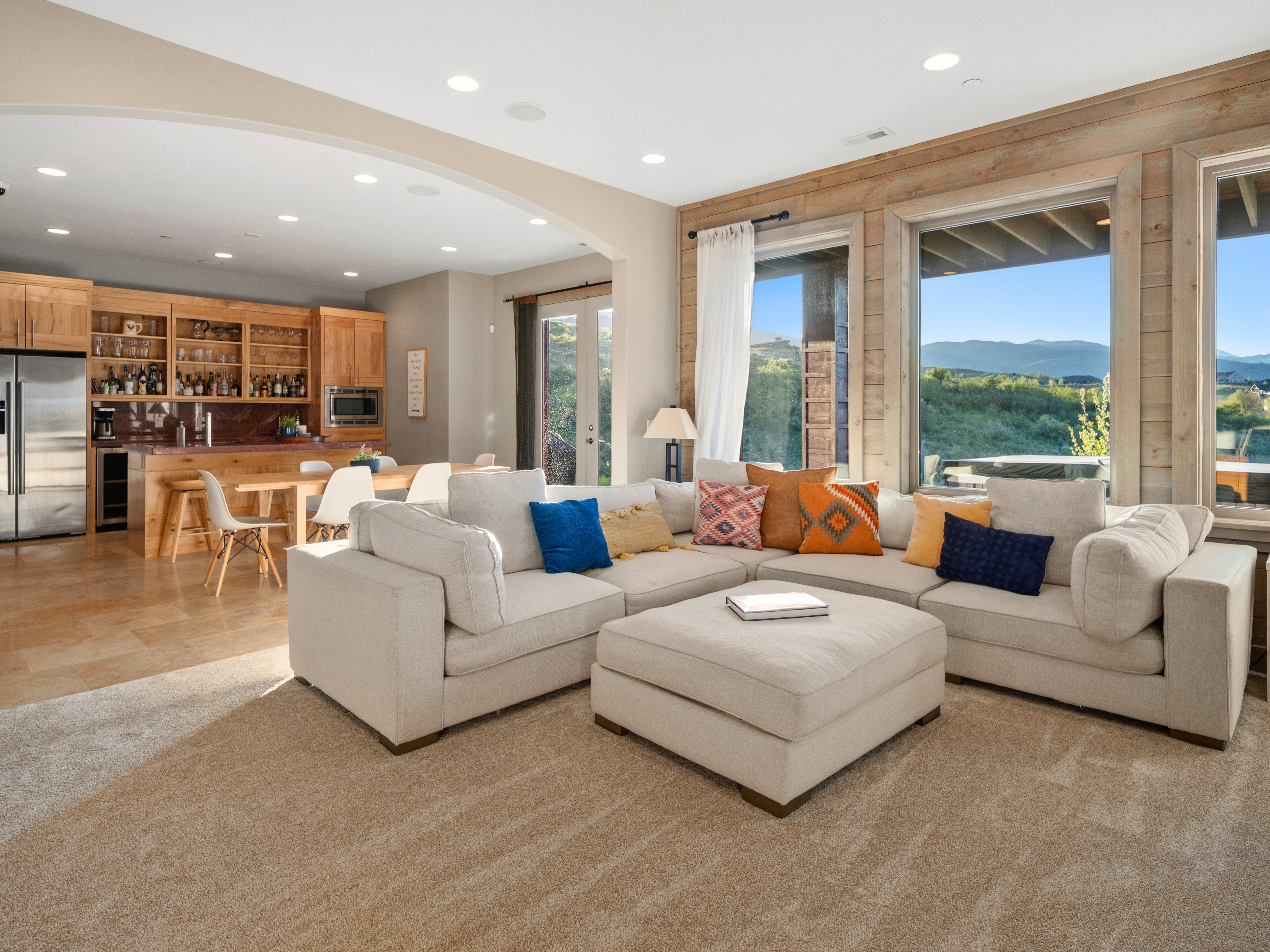 Open-concept living space featuring a large sectional, wood-finish flooring, and a kitchen with custom cabinetry