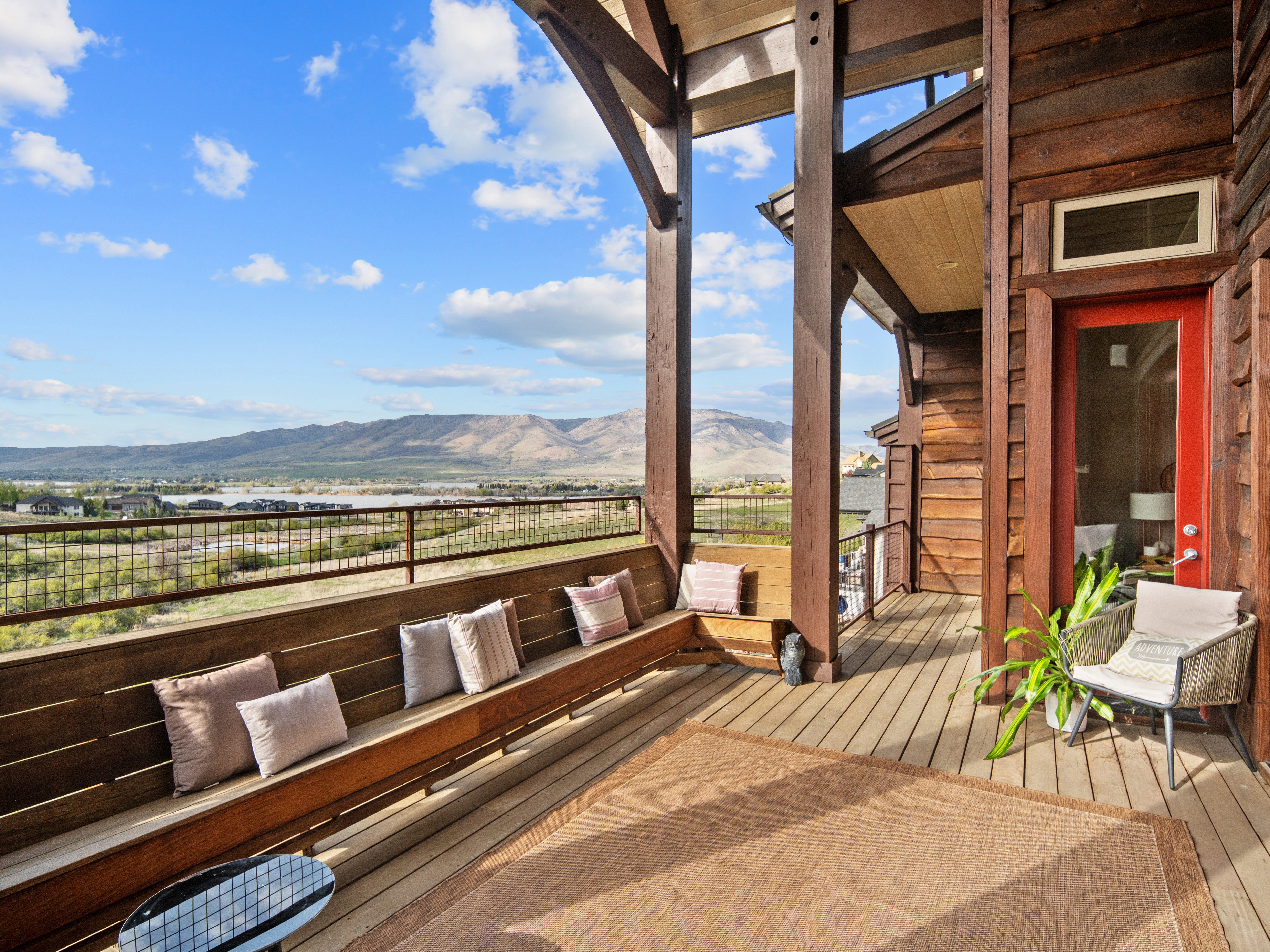 Expansive outdoor deck featuring wood-finish flooring, a built-in bench, and a metal railing