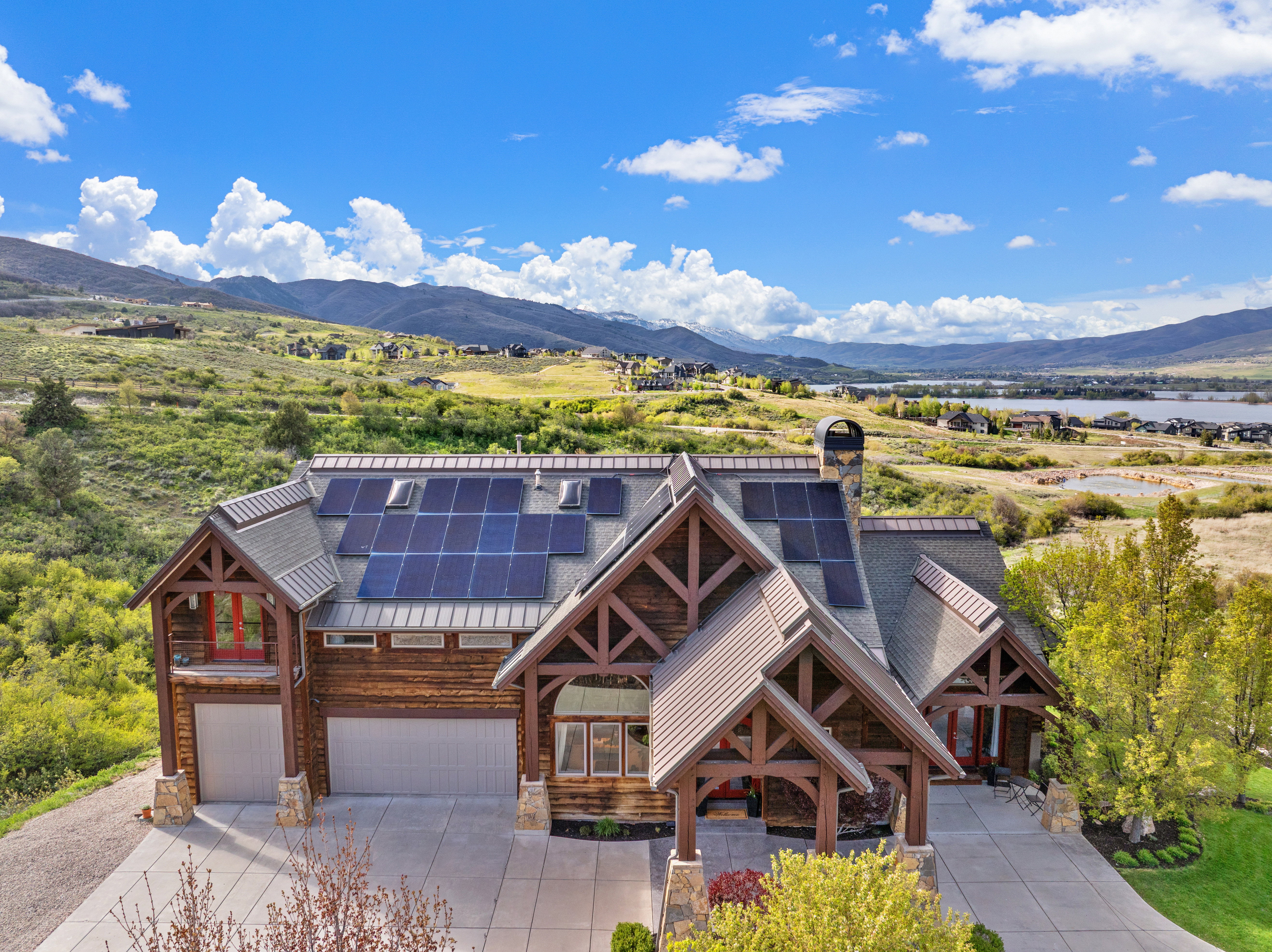 Log home exterior with a prominent entry porch, solar panels, and a two-car garage