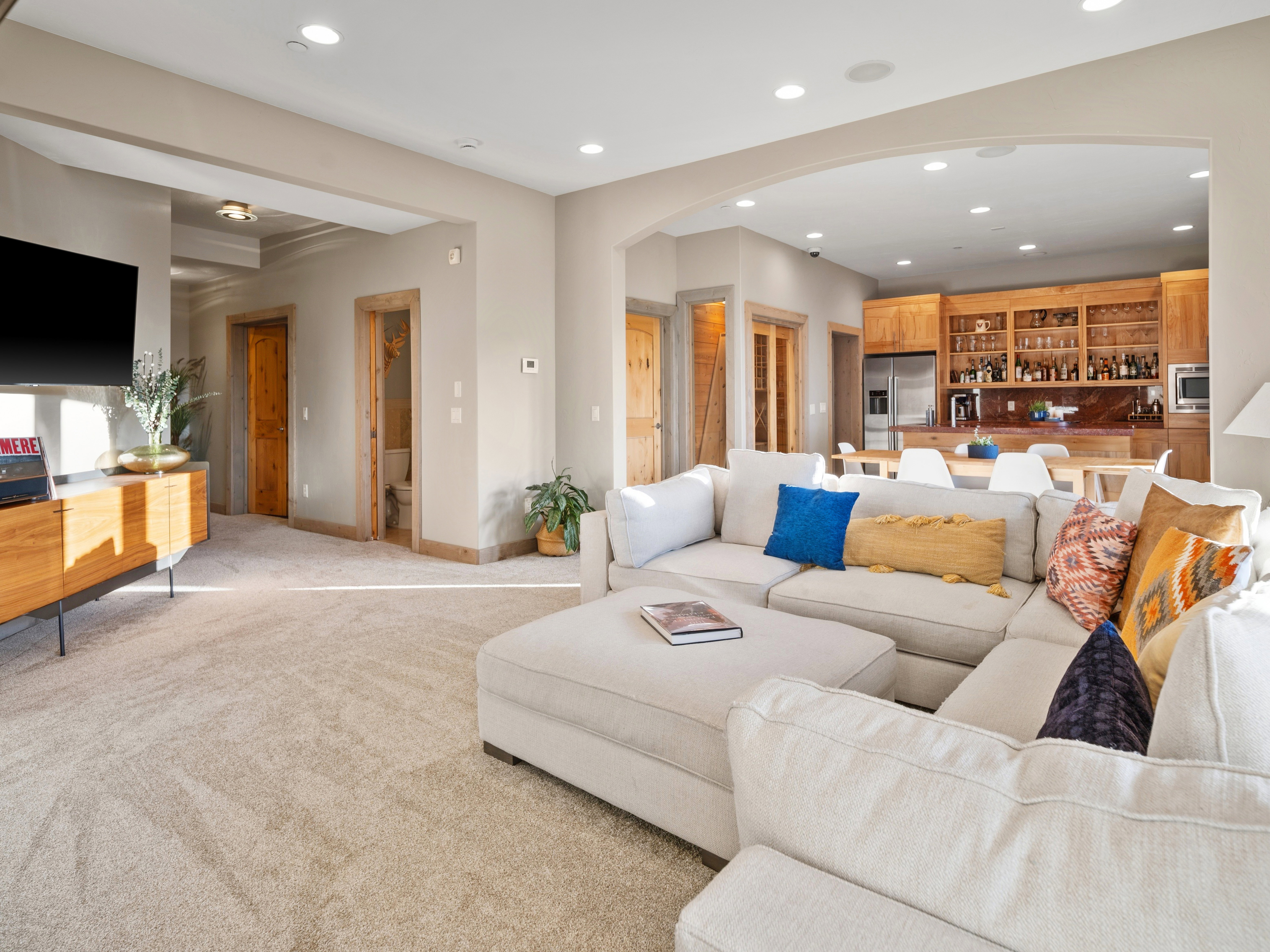 Open-concept living space featuring recessed lighting, light-toned carpeting, and natural wood trim throughout