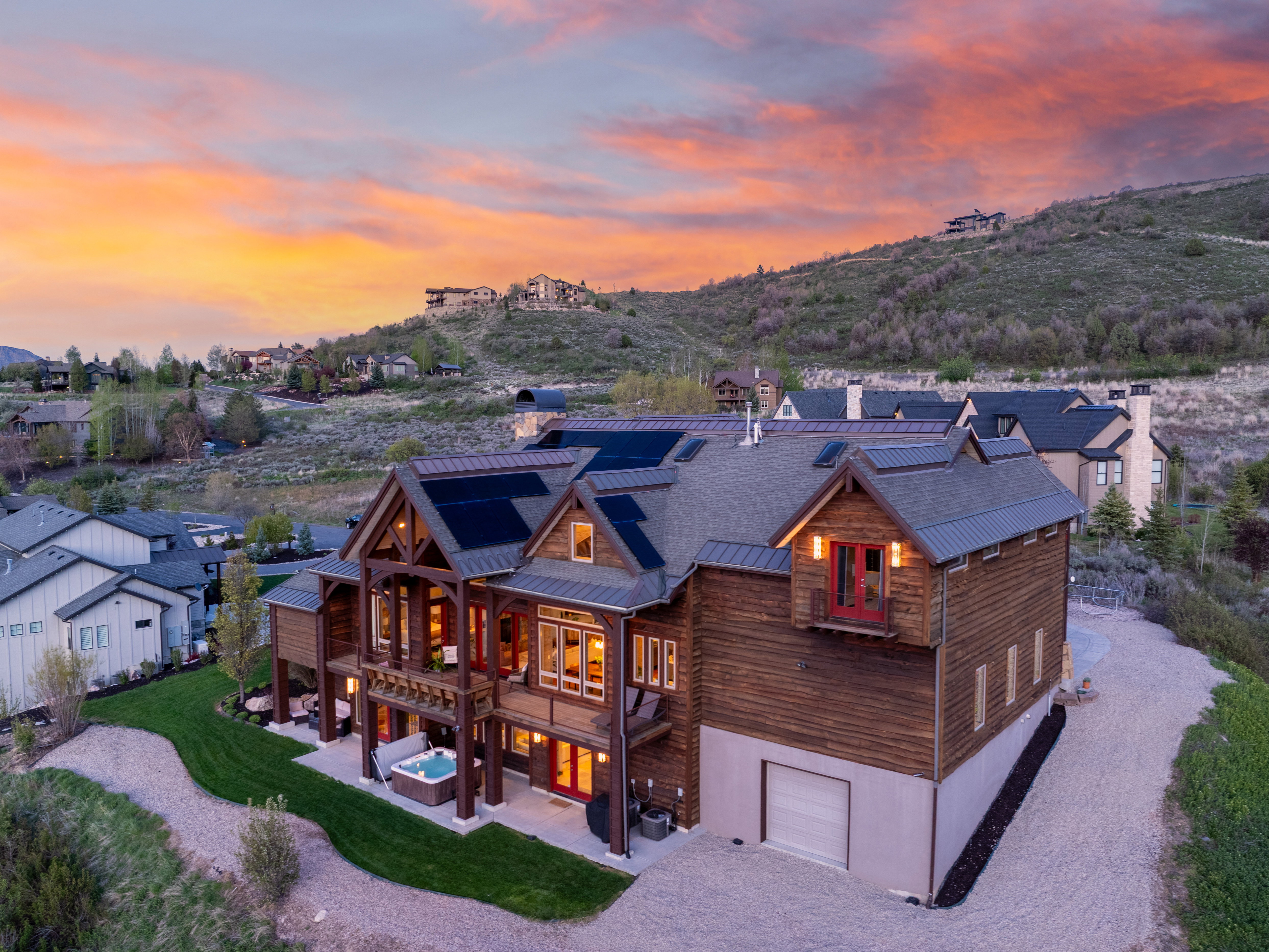 Multi-level architectural design featuring extensive wood siding, multiple balconies, and an integrated hot tub on a ground-level patio