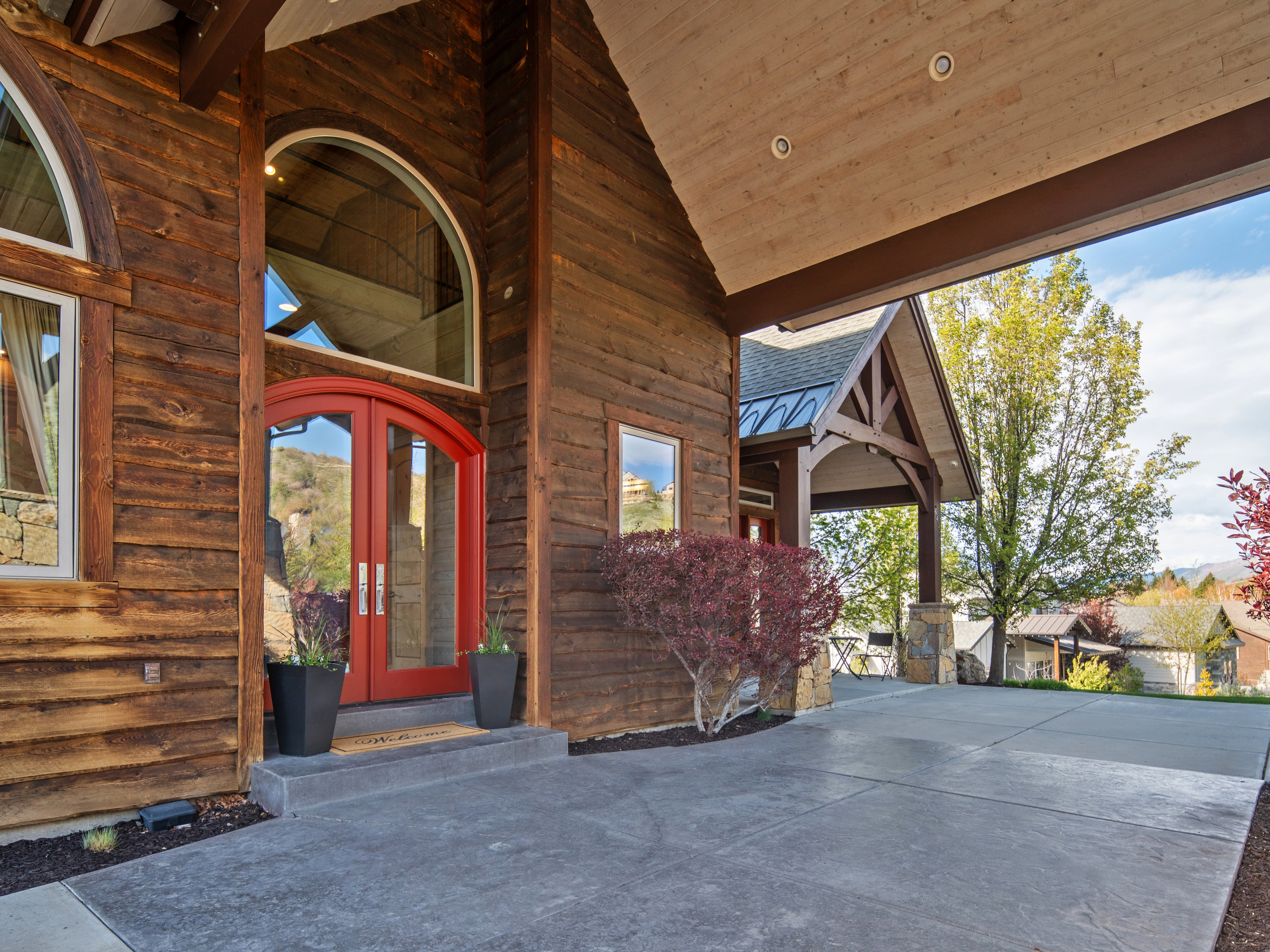 Rustic wood siding exterior featuring an arched double-door entry with transom window