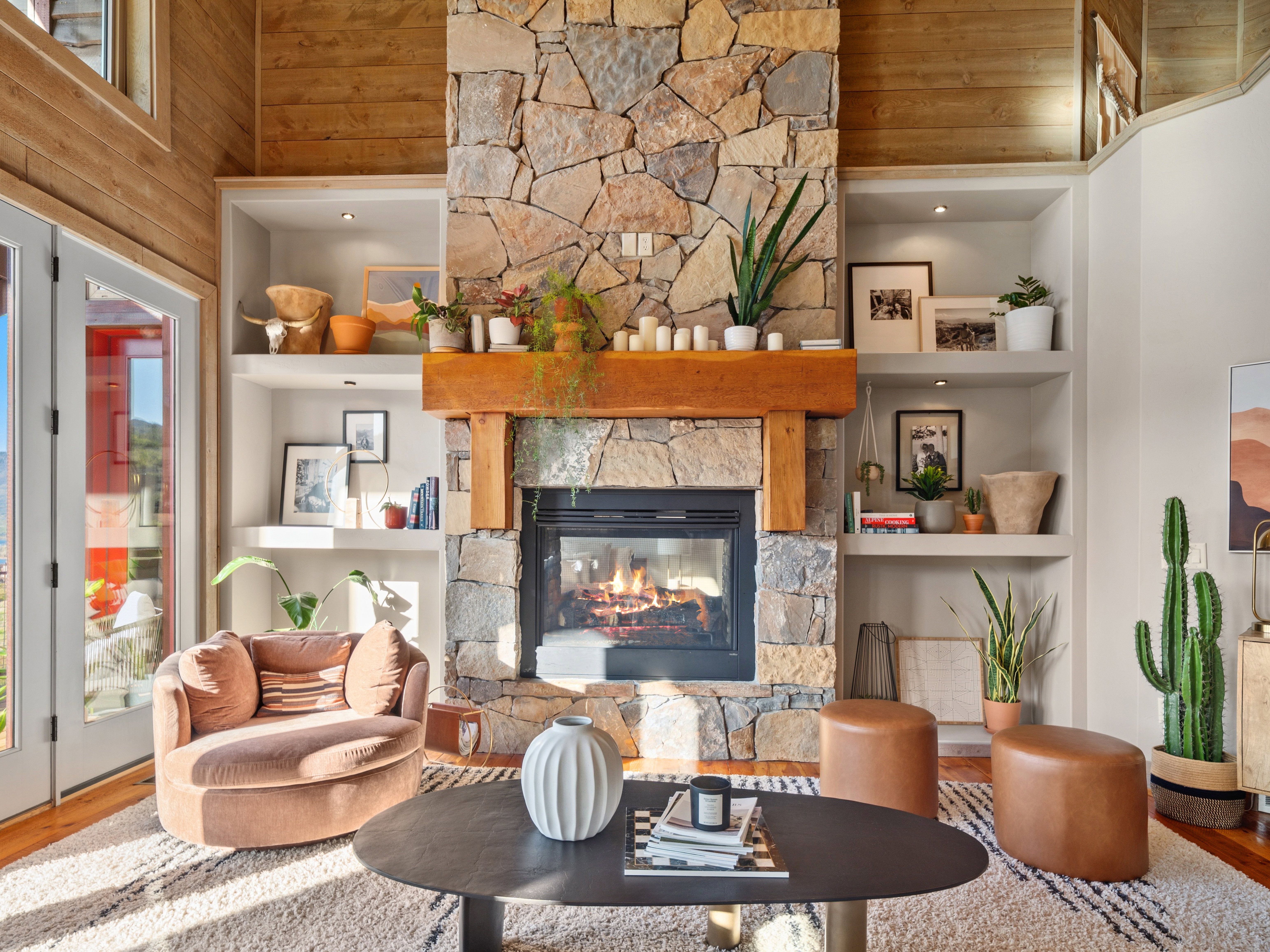 Stone fireplace with a substantial wood mantel, flanked by built-in shelving with integrated lighting