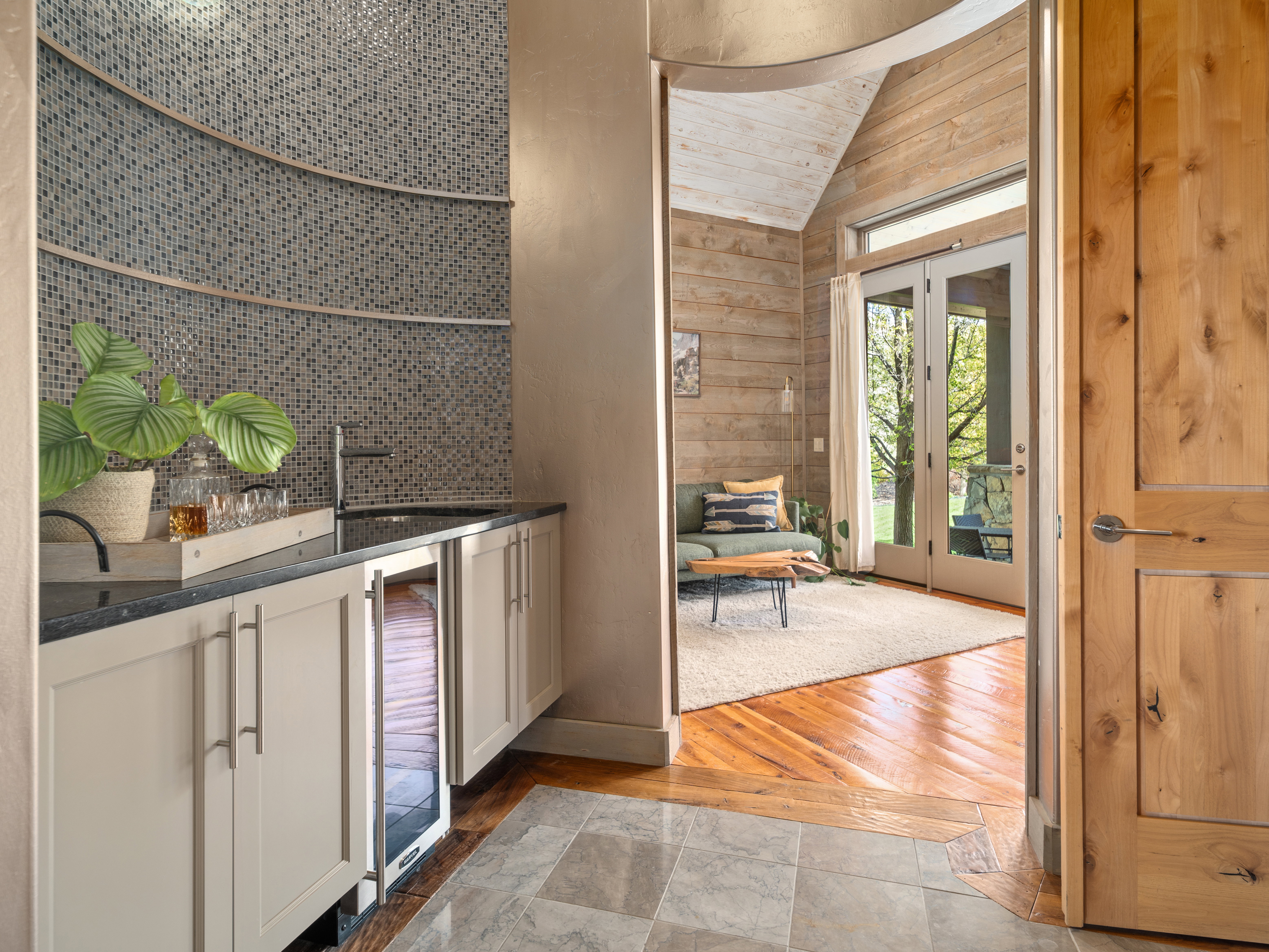 Wet bar with mosaic tile backsplash, integrated beverage cooler, and dark countertop