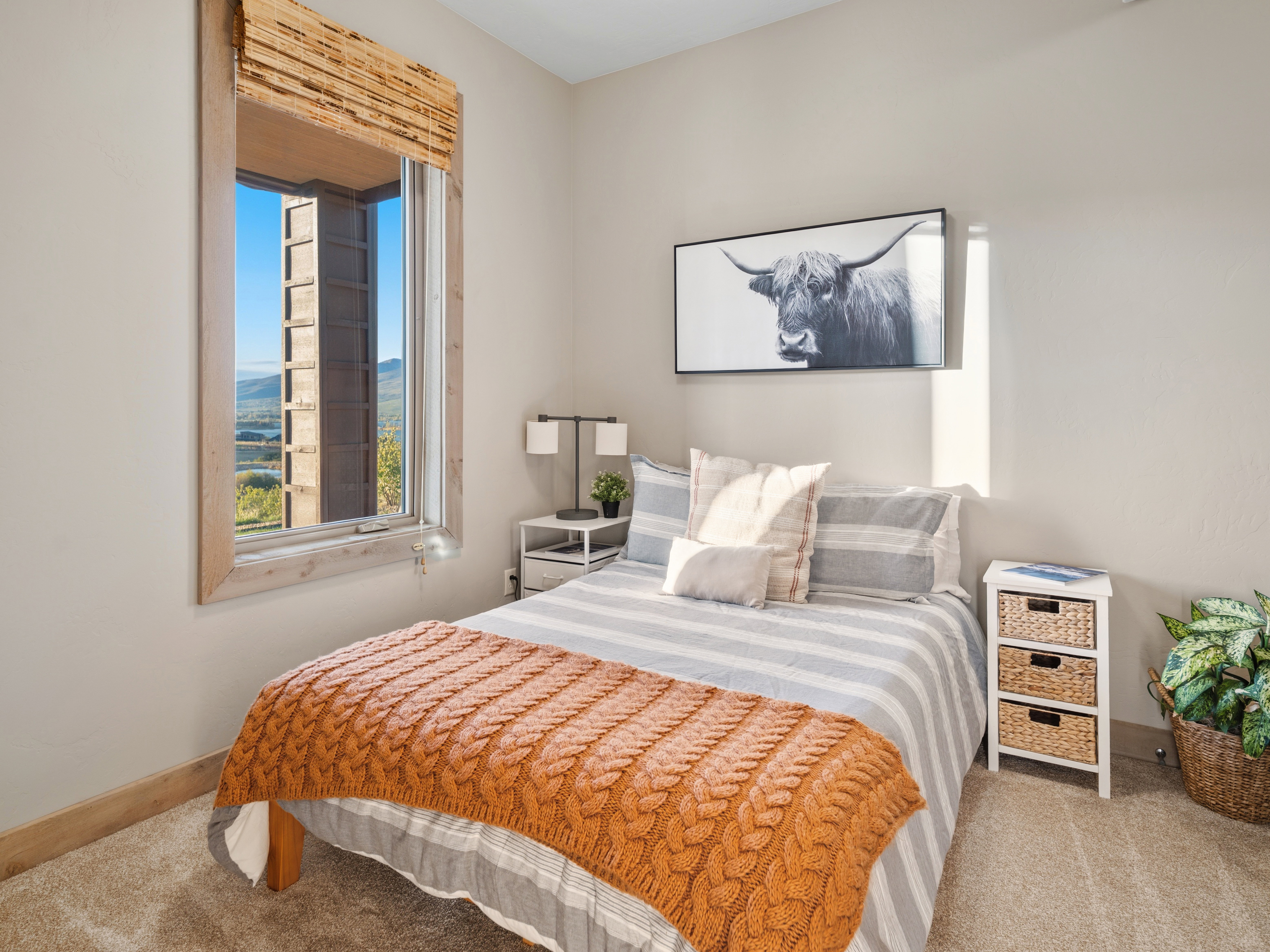 Expansive window with wood-finish trim, offering distant mountain and lake scenery