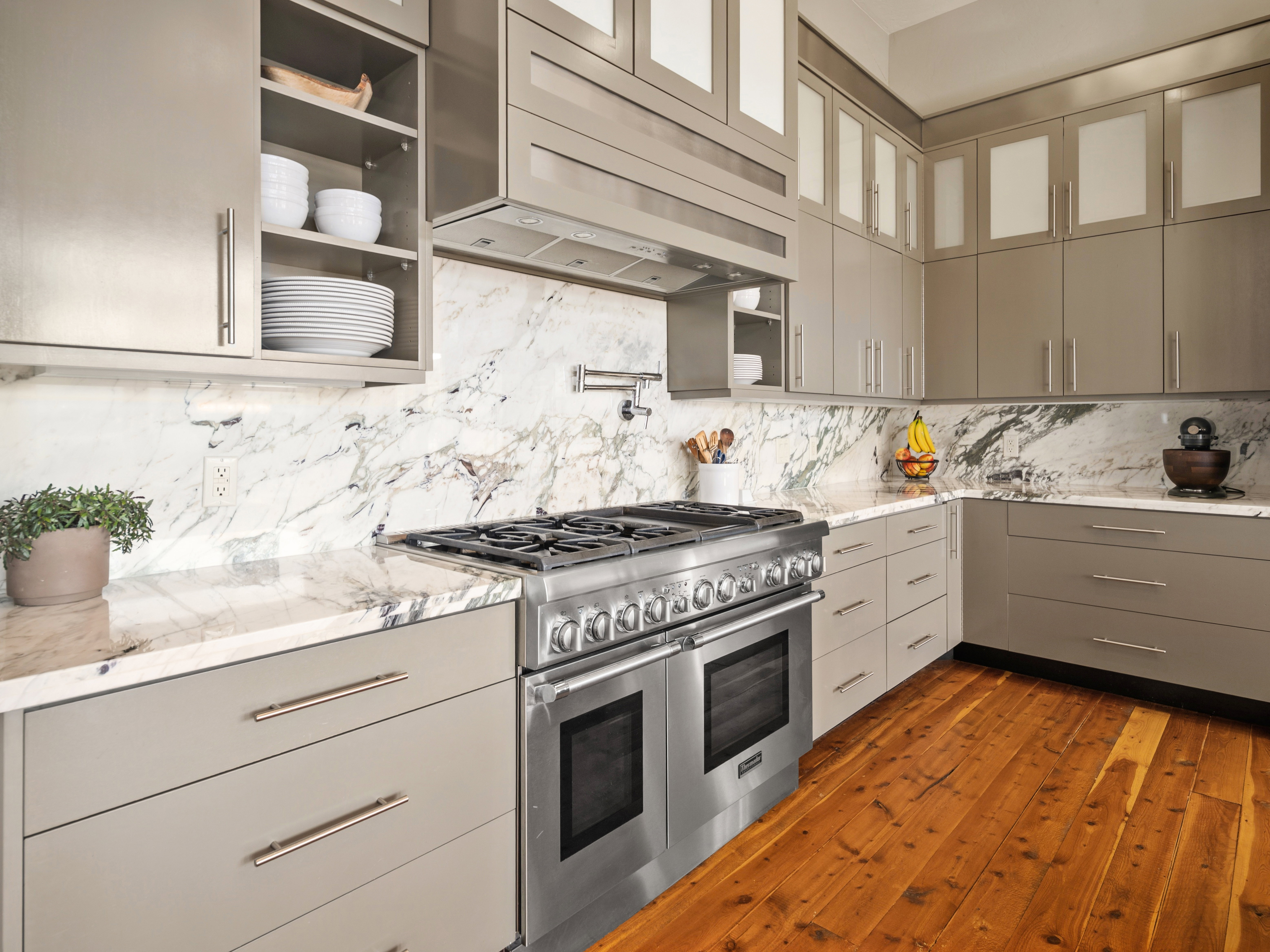 Kitchen featuring a professional-grade stainless steel range with double ovens, a complementary hood, and a pot filler