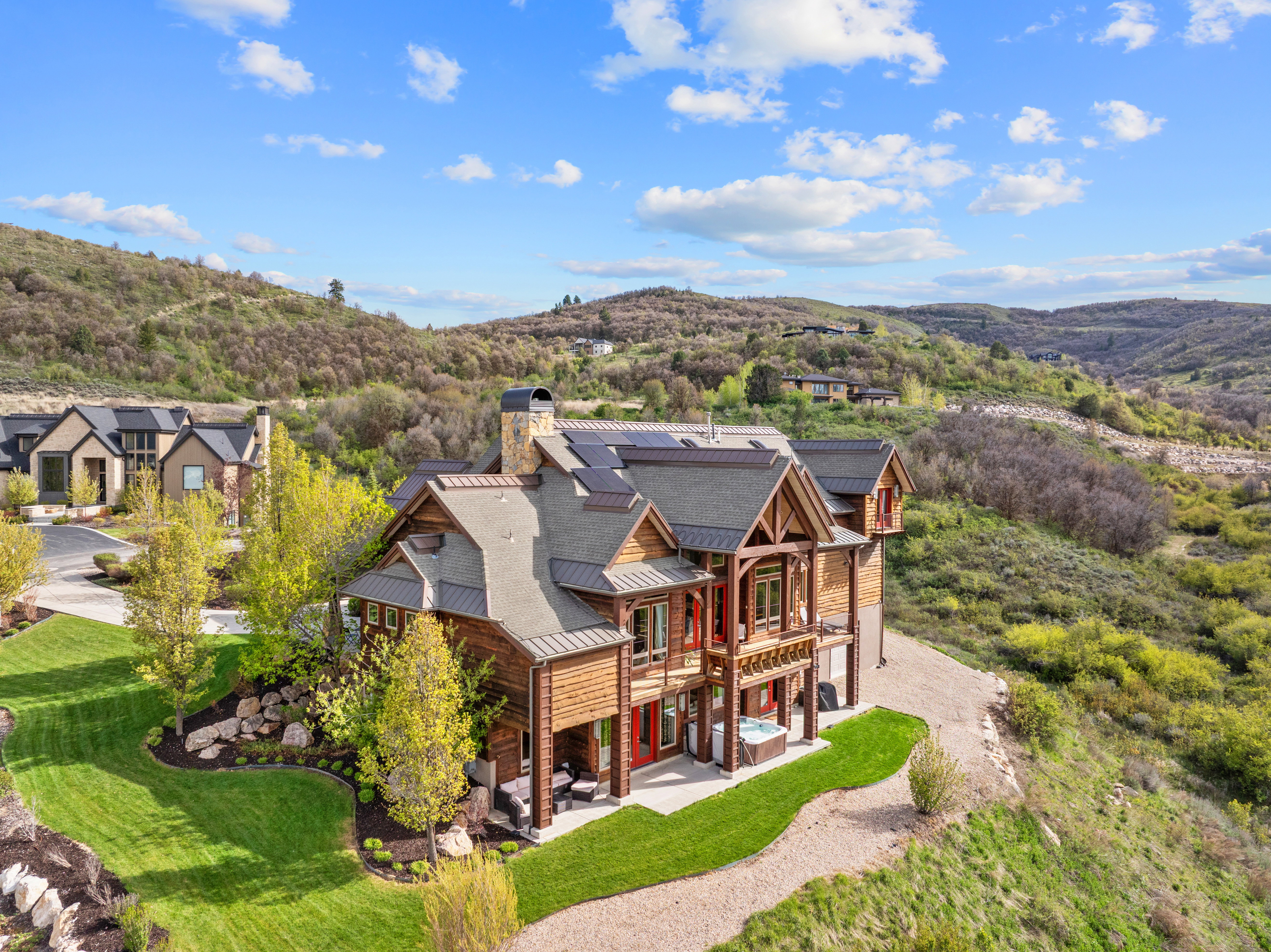 Craftsman-style home featuring extensive wood siding, a stone chimney, and multiple gables
