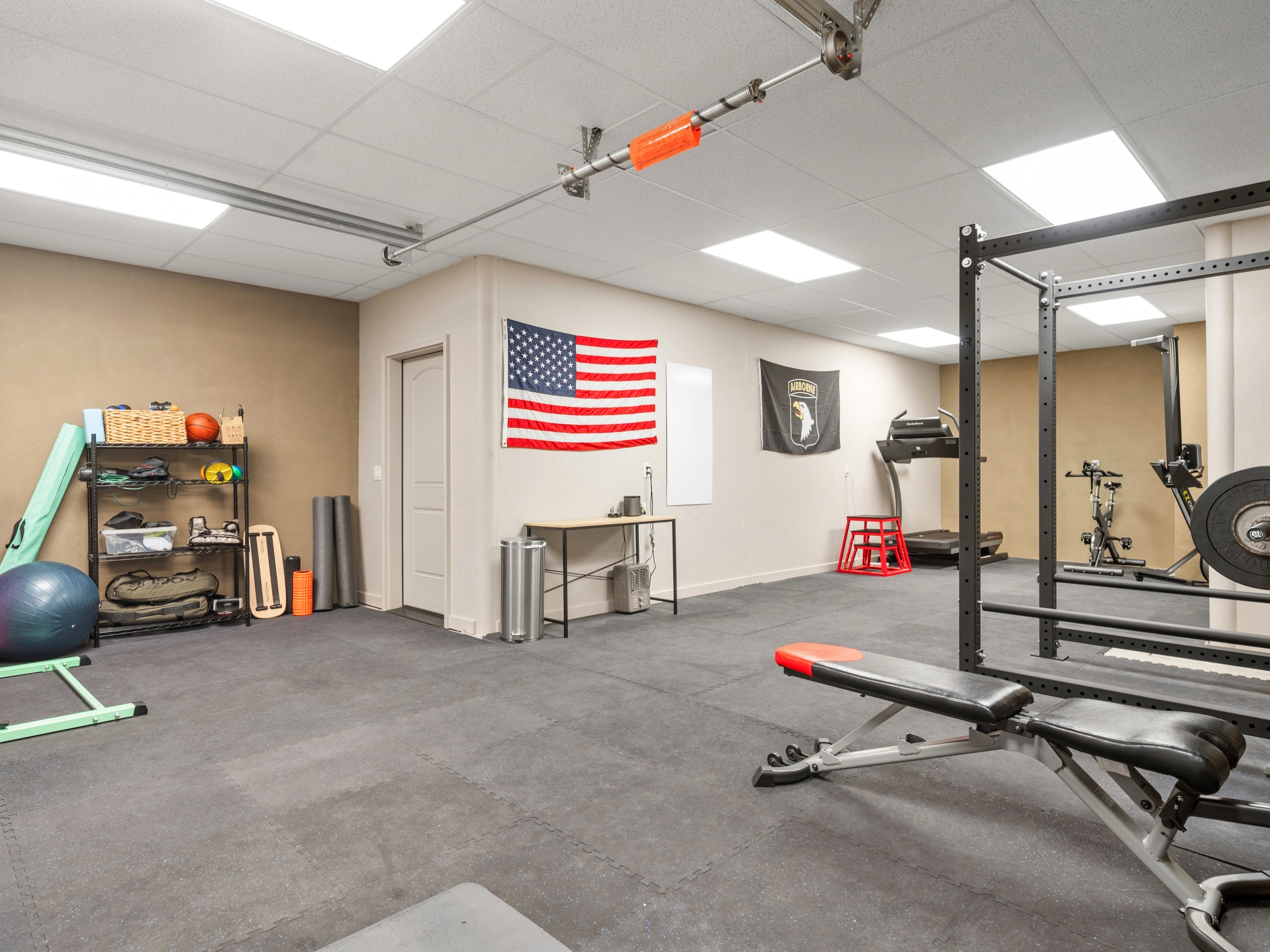 Spacious room featuring ceiling-mounted fluorescent lighting, a drop ceiling, and durable interlocking floor mats