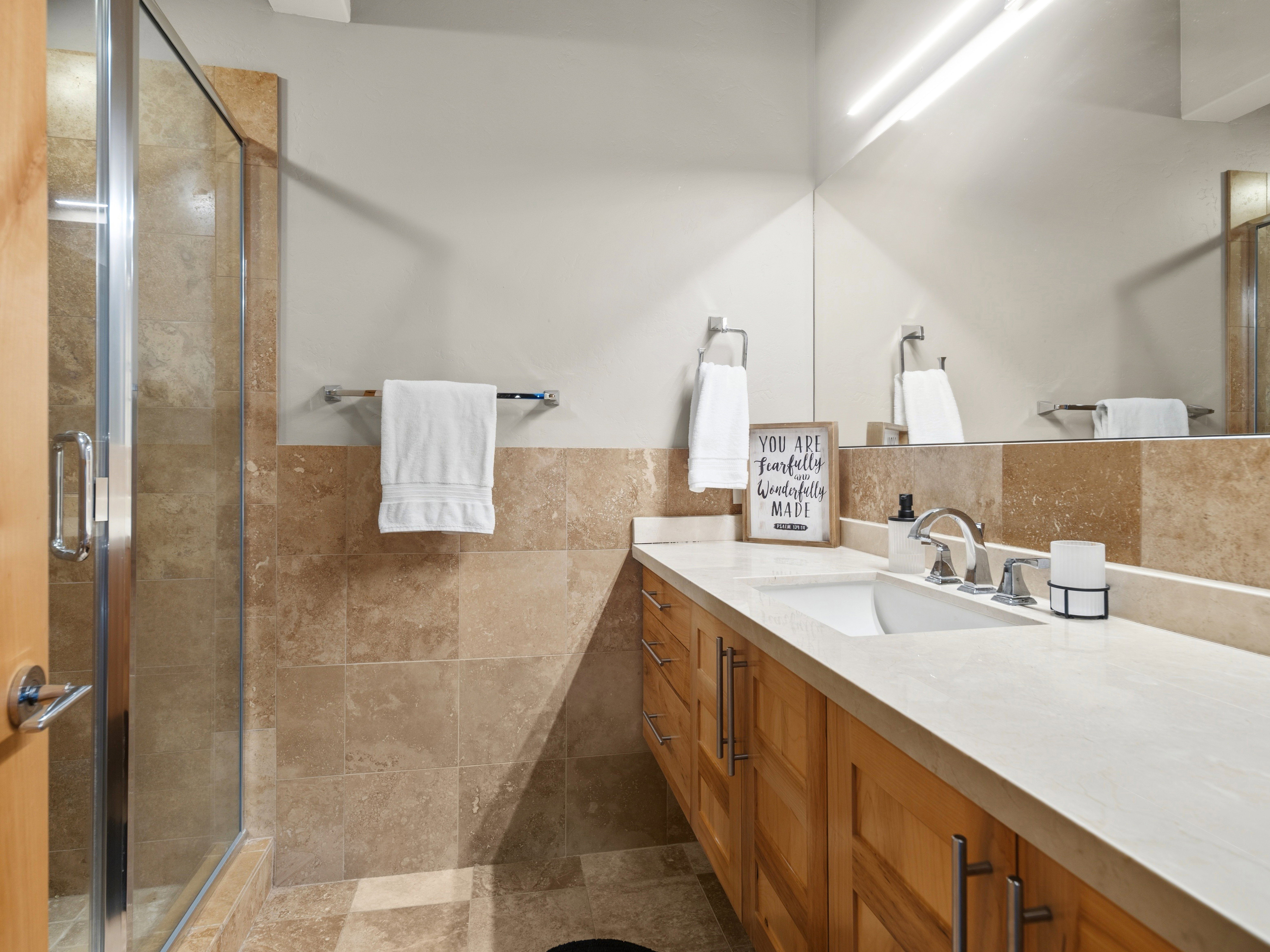 Bathroom featuring a light wood vanity with a white countertop, an integrated rectangular sink, and a chrome faucet