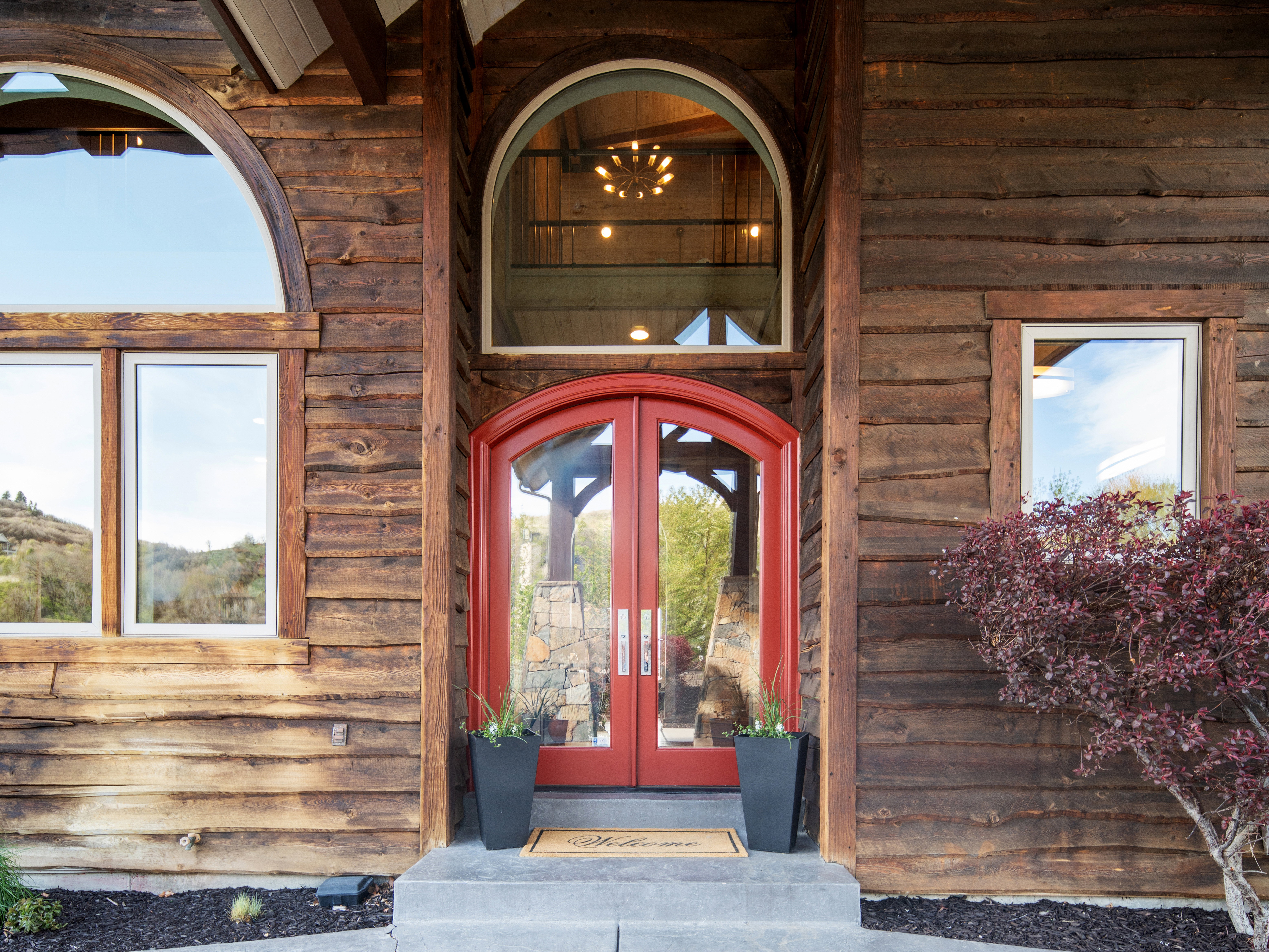 Rustic wood siding exterior featuring a red arched double-door entry