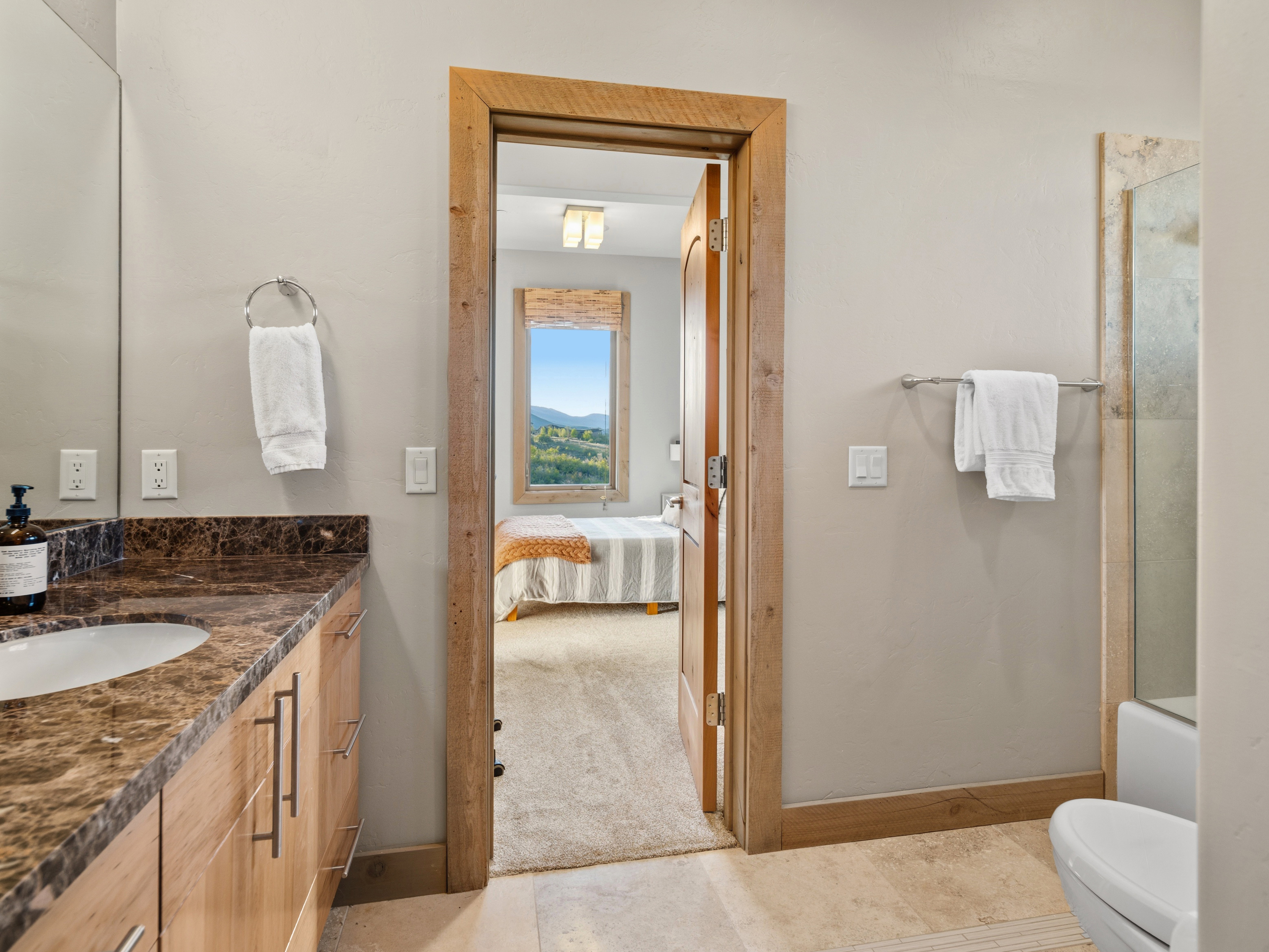 Bathroom featuring a wood-finish vanity with a drop-in sink and a patterned countertop