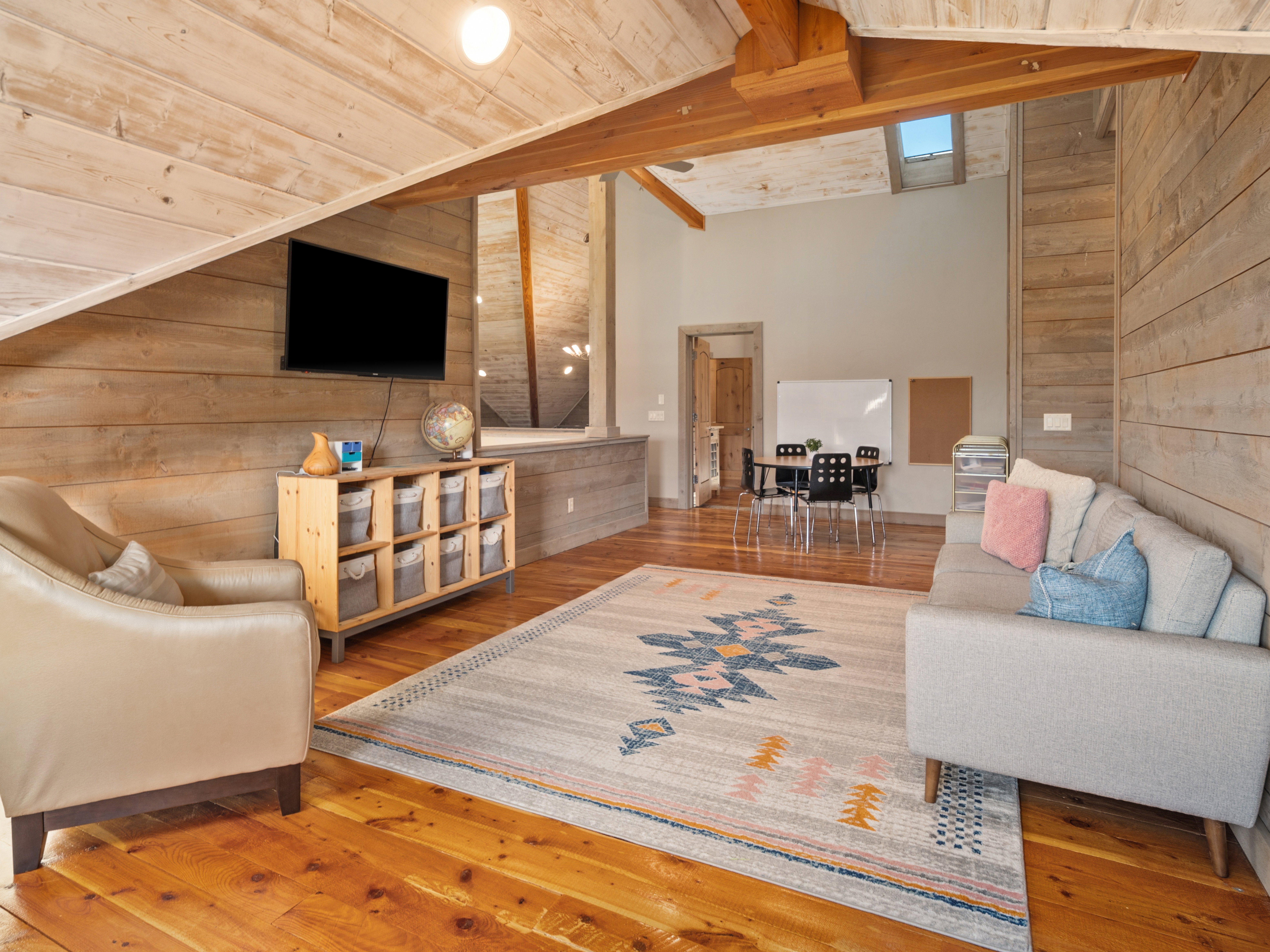 Vaulted ceiling with exposed wood beams, skylight, and wood-paneled walls