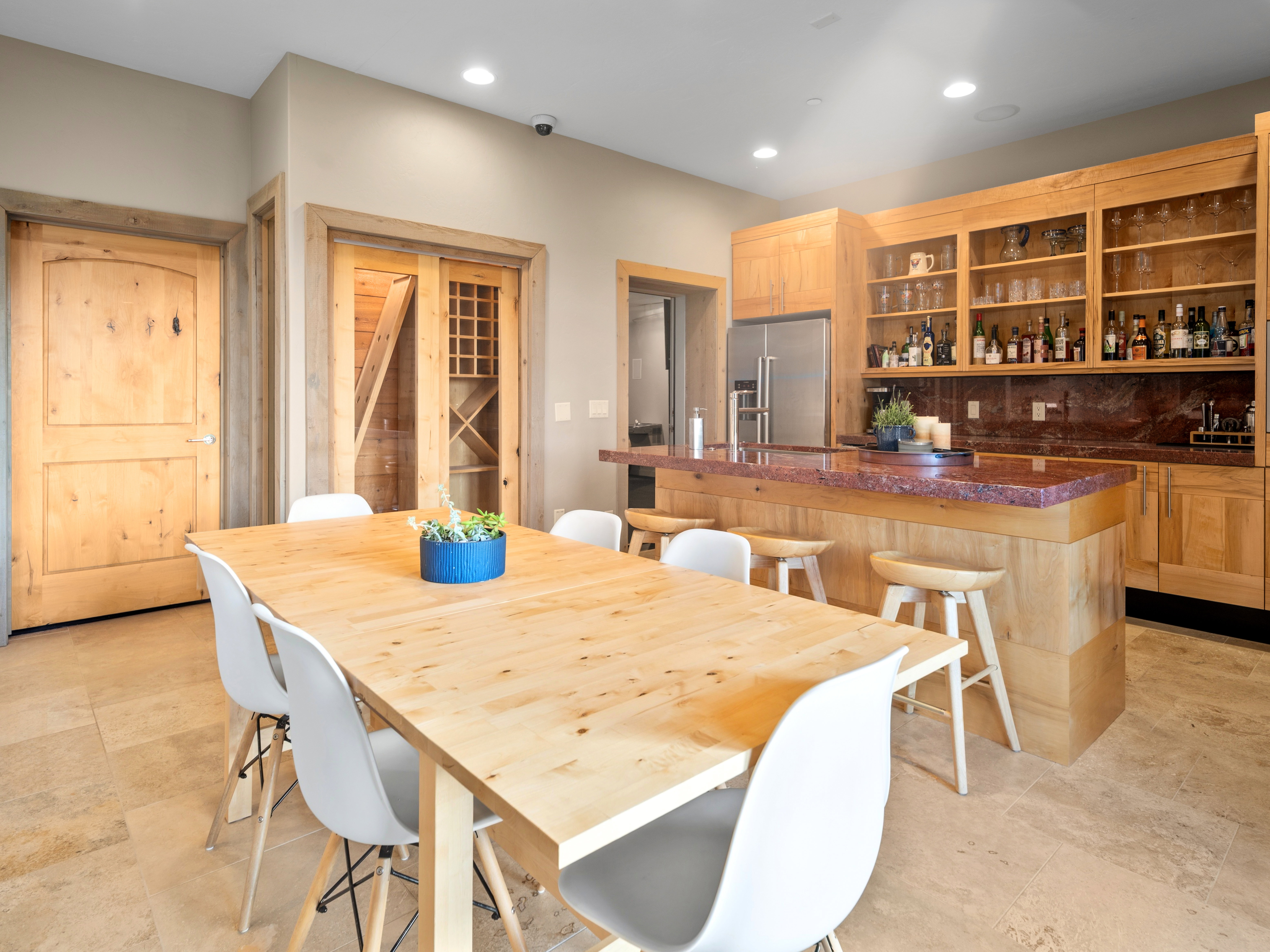 Open-concept space featuring a built-in bar with a red countertop, integrated shelving, and a stainless steel refrigerator
