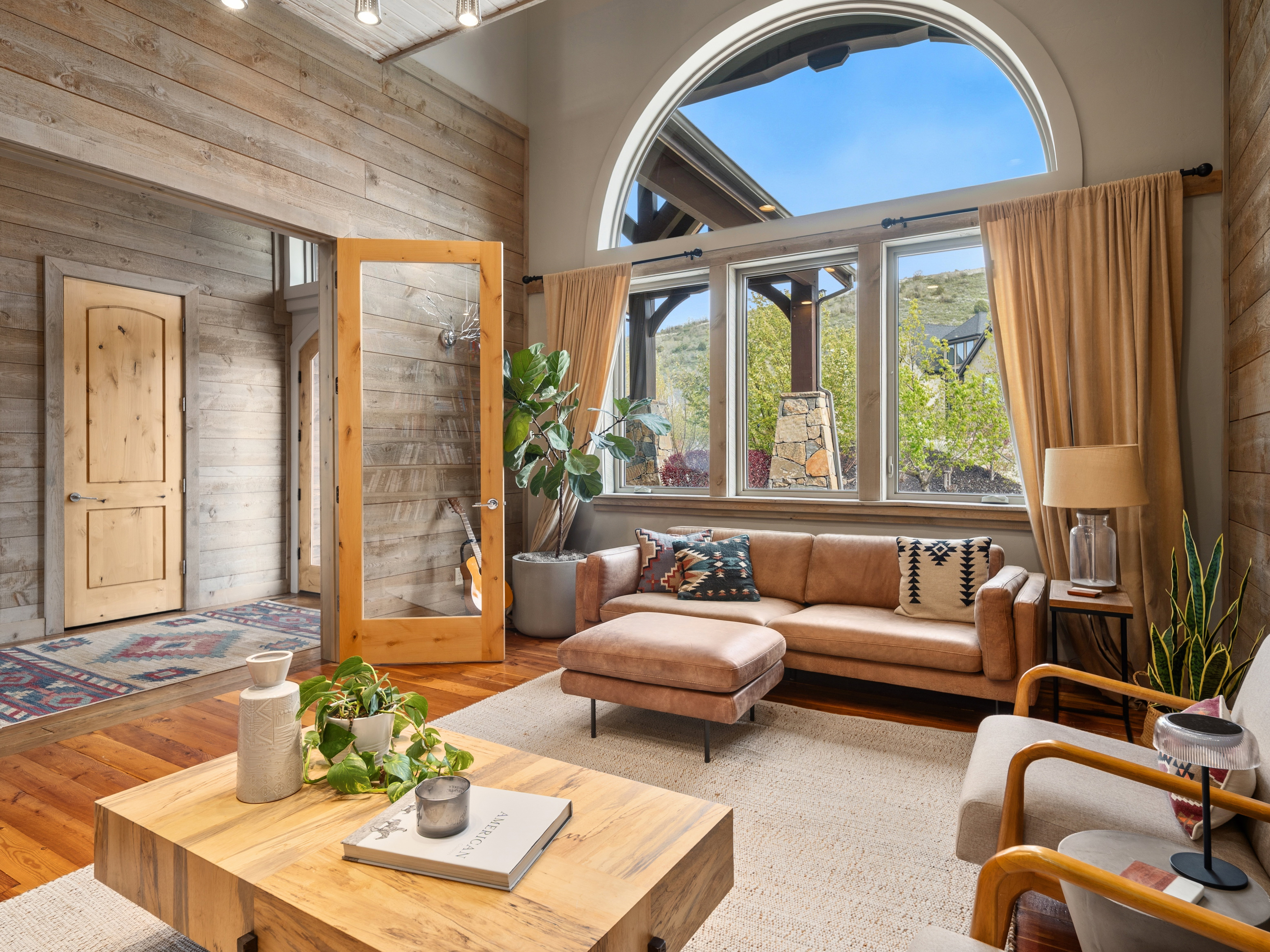 Spacious living area featuring a large arched window, wood-finish flooring, and recessed ceiling lighting