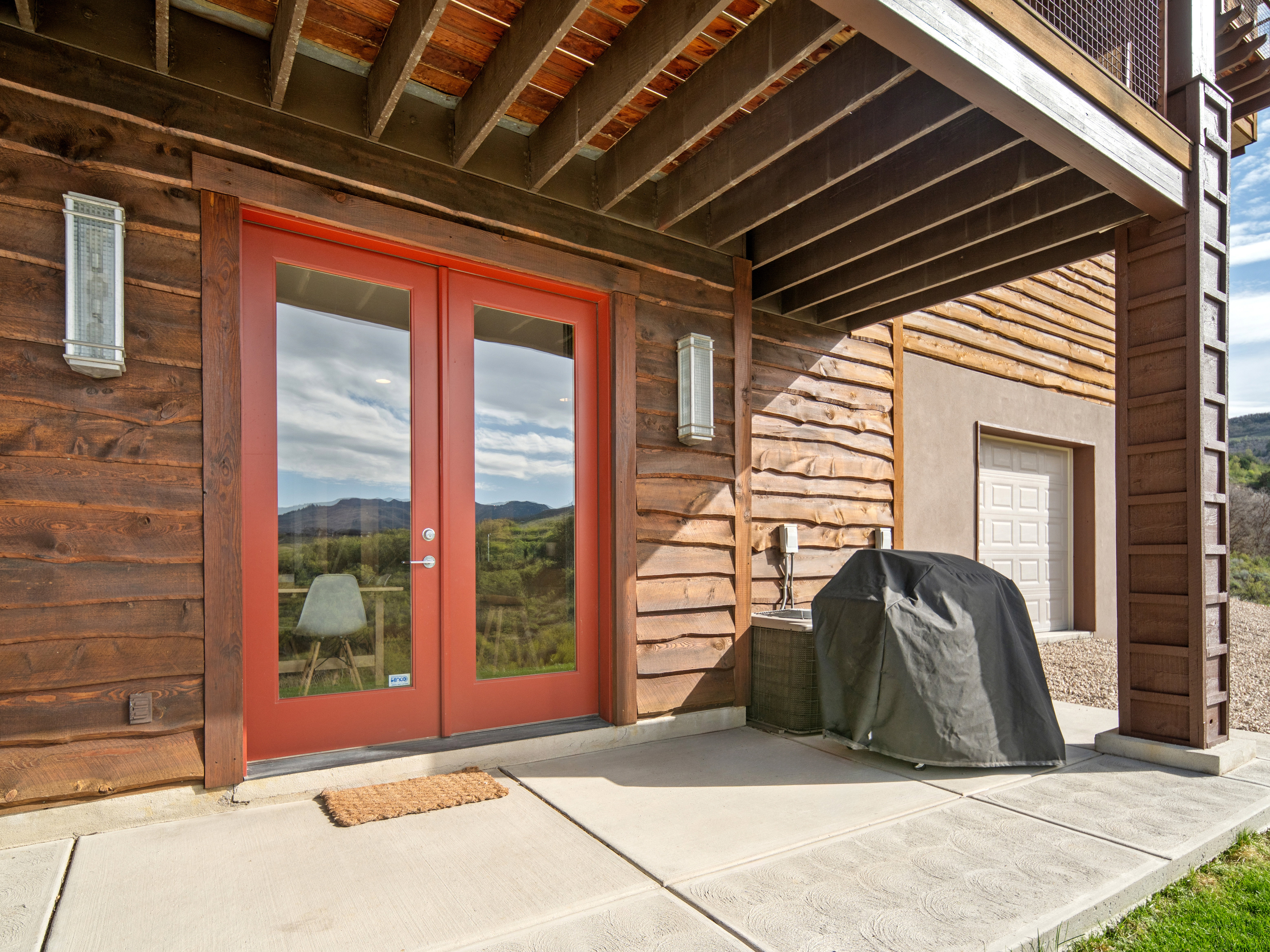 Concrete patio with French doors, wood paneling, and an exposed wood beam ceiling