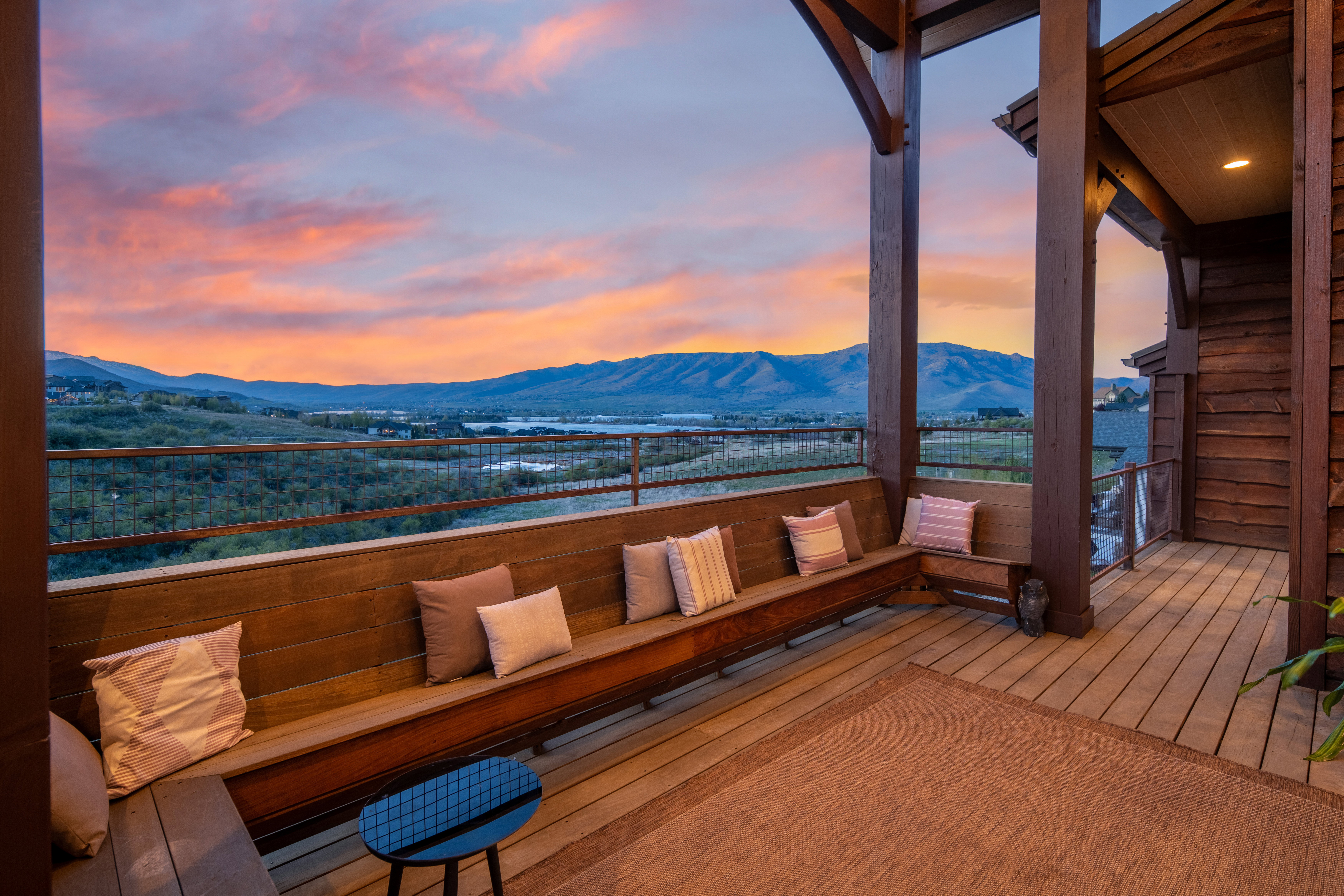 Expansive covered deck featuring wood-finish flooring and a built-in wooden bench
