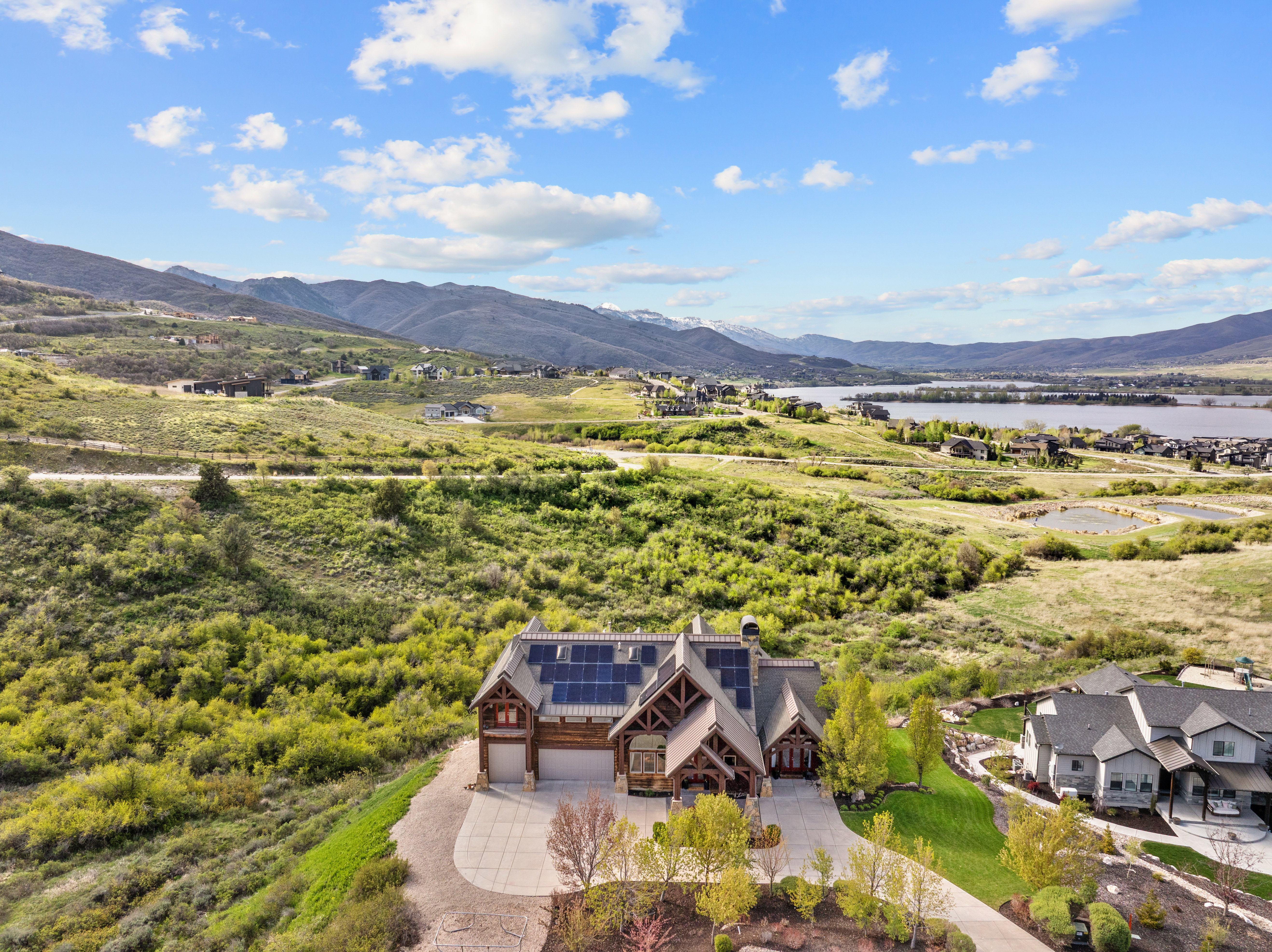 Mountain-modern residence featuring a prominent gabled roofline, solar panel array, and a paved circular driveway