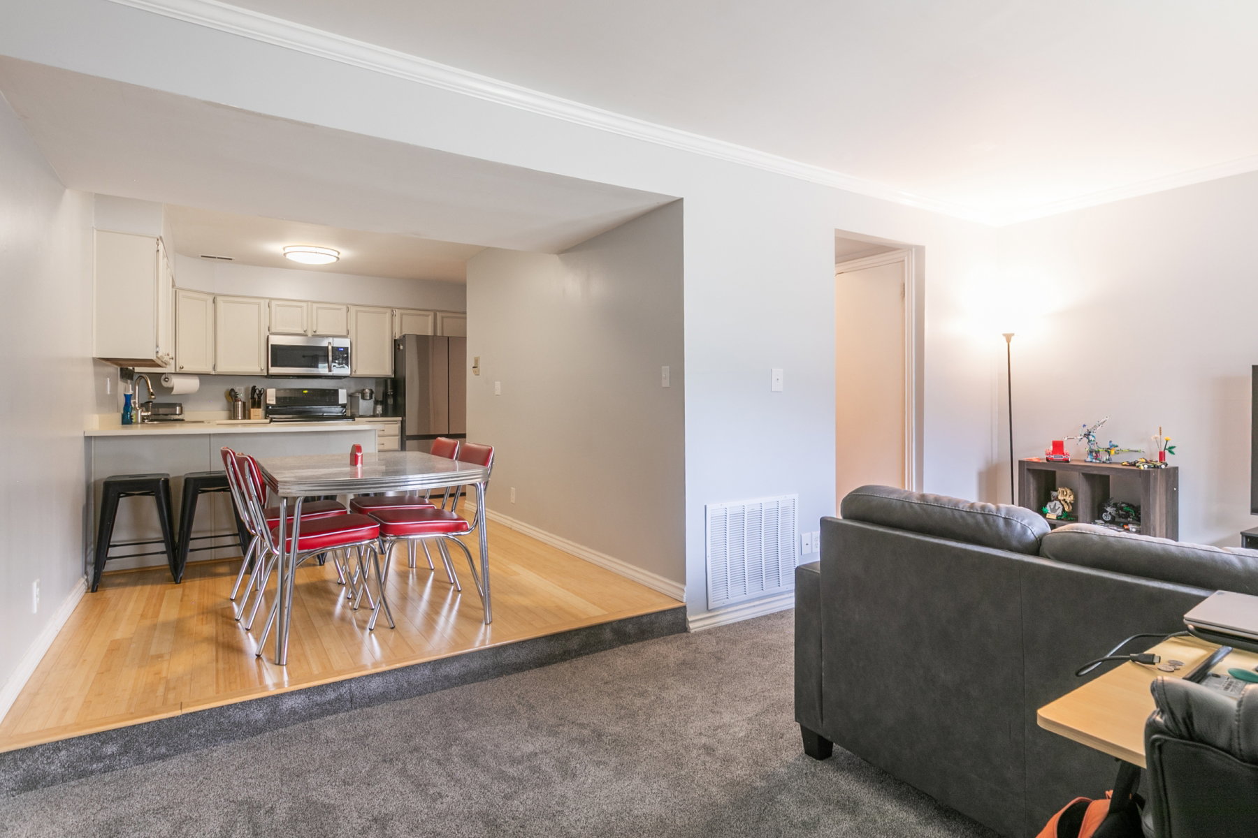 Kitchen and dining area featuring wood-finish flooring, white cabinetry, stainless steel appliances, and a breakfast bar with seating