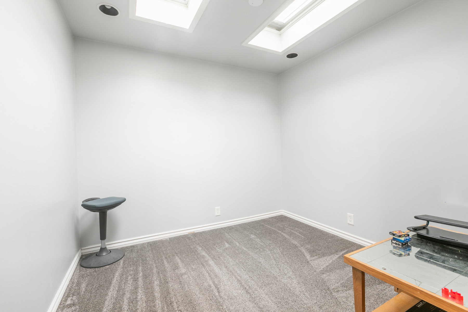 Recessed lighting and two skylights illuminate this room with light gray walls and gray patterned carpeting