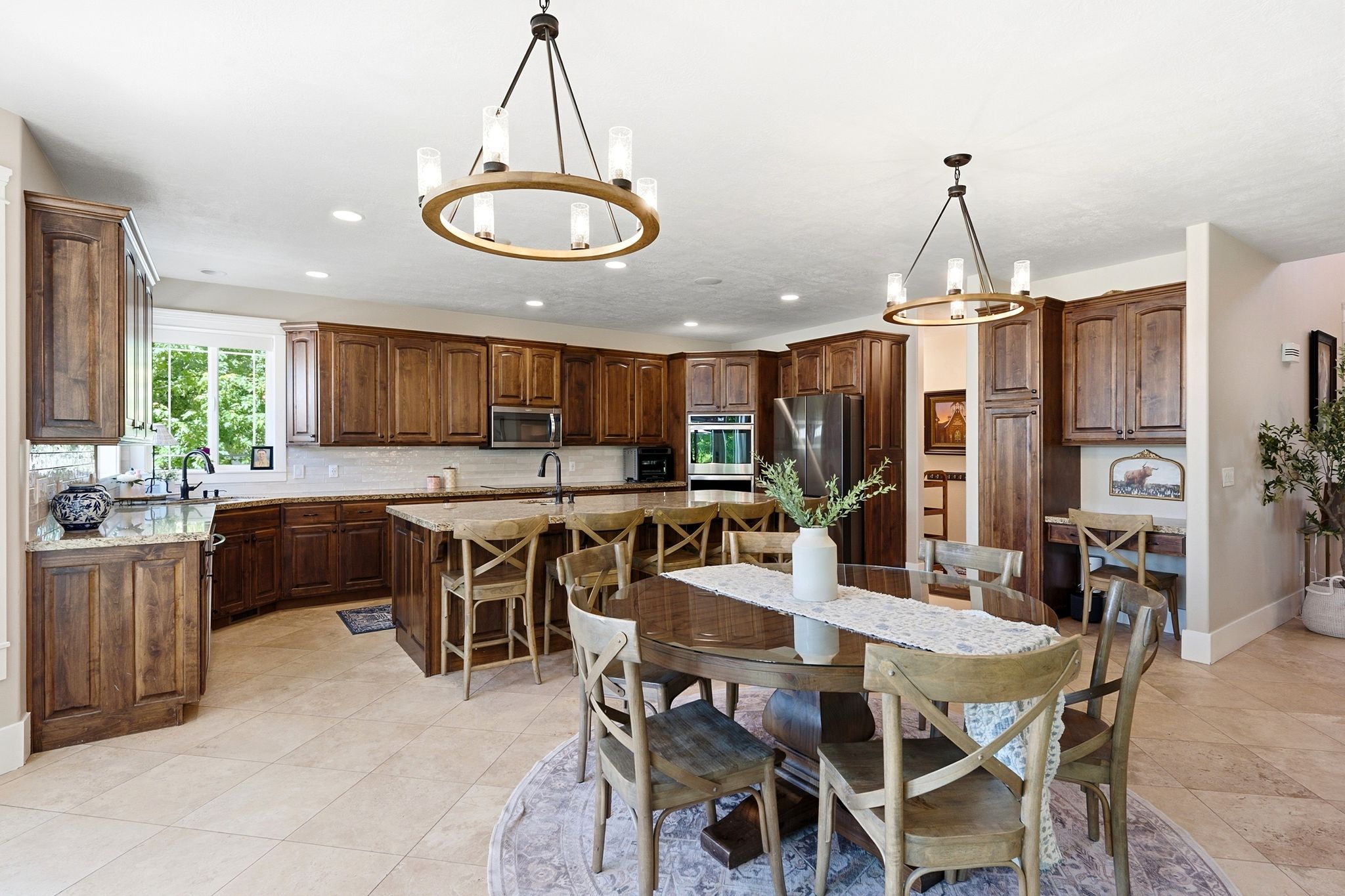 Spacious kitchen featuring extensive wood cabinetry, light-toned stone countertops, and tile flooring
